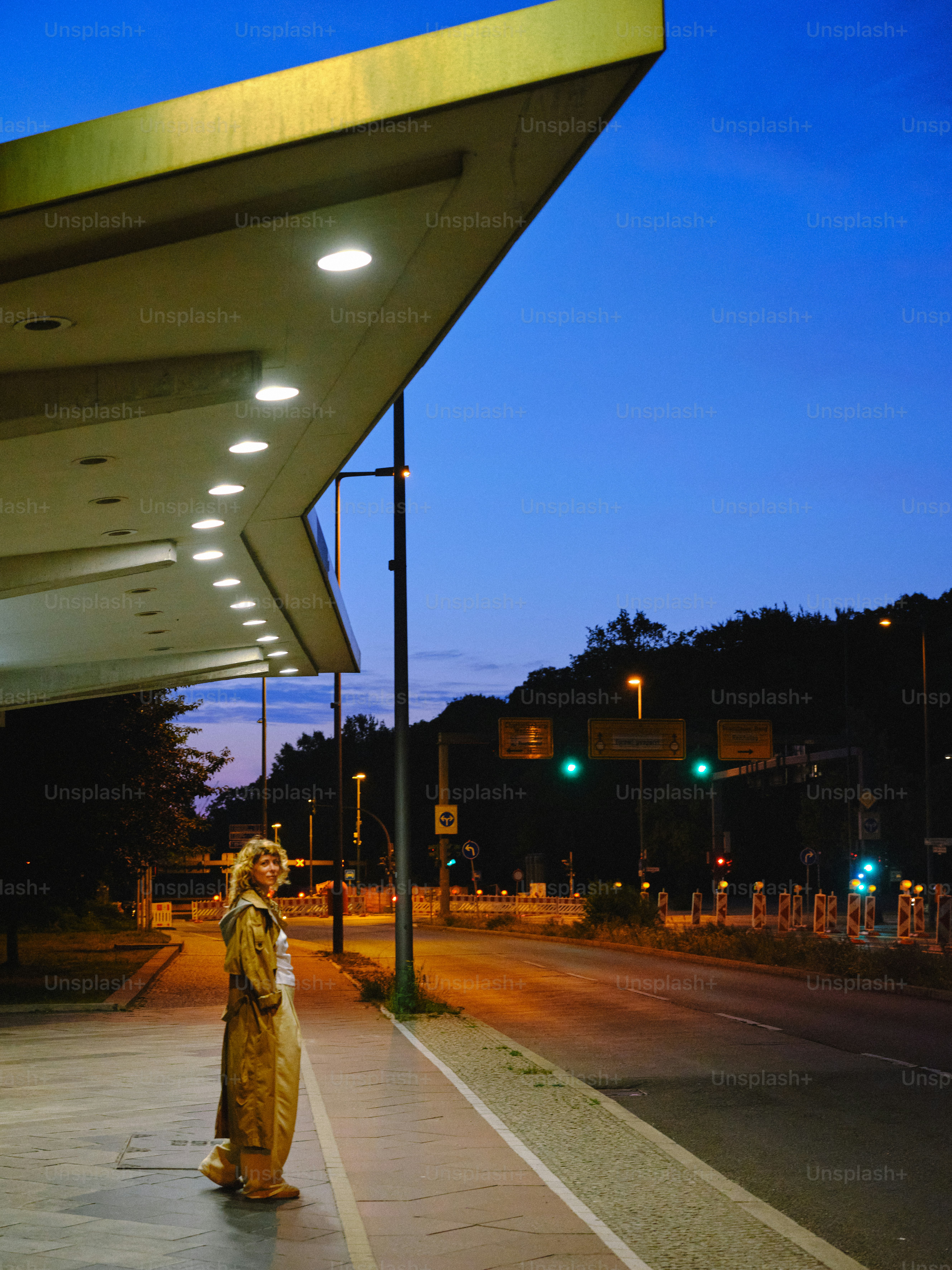 Mulher fica em um ponto de ônibus ao anoitecer.