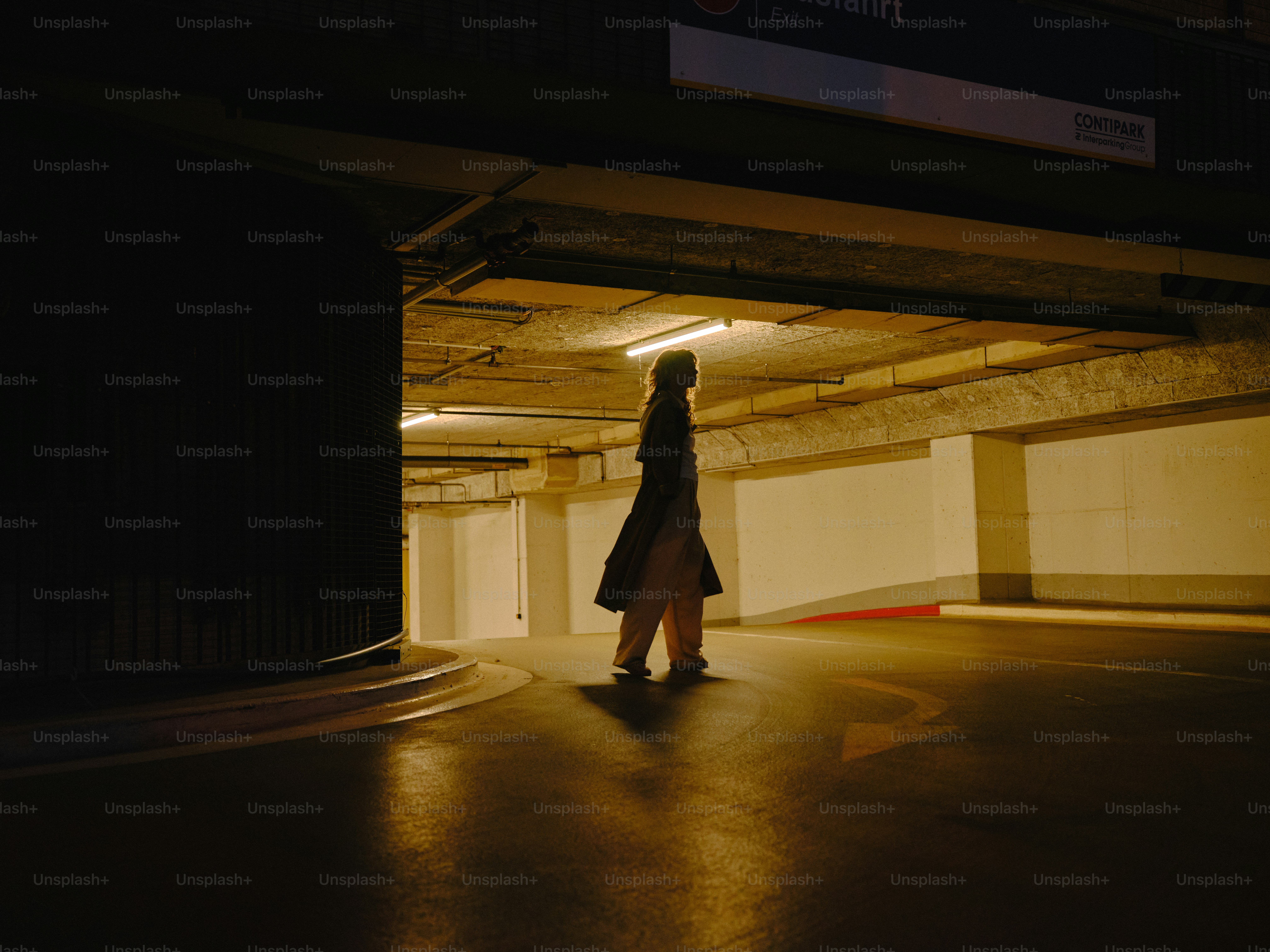 A person walks in a dark parking garage.
