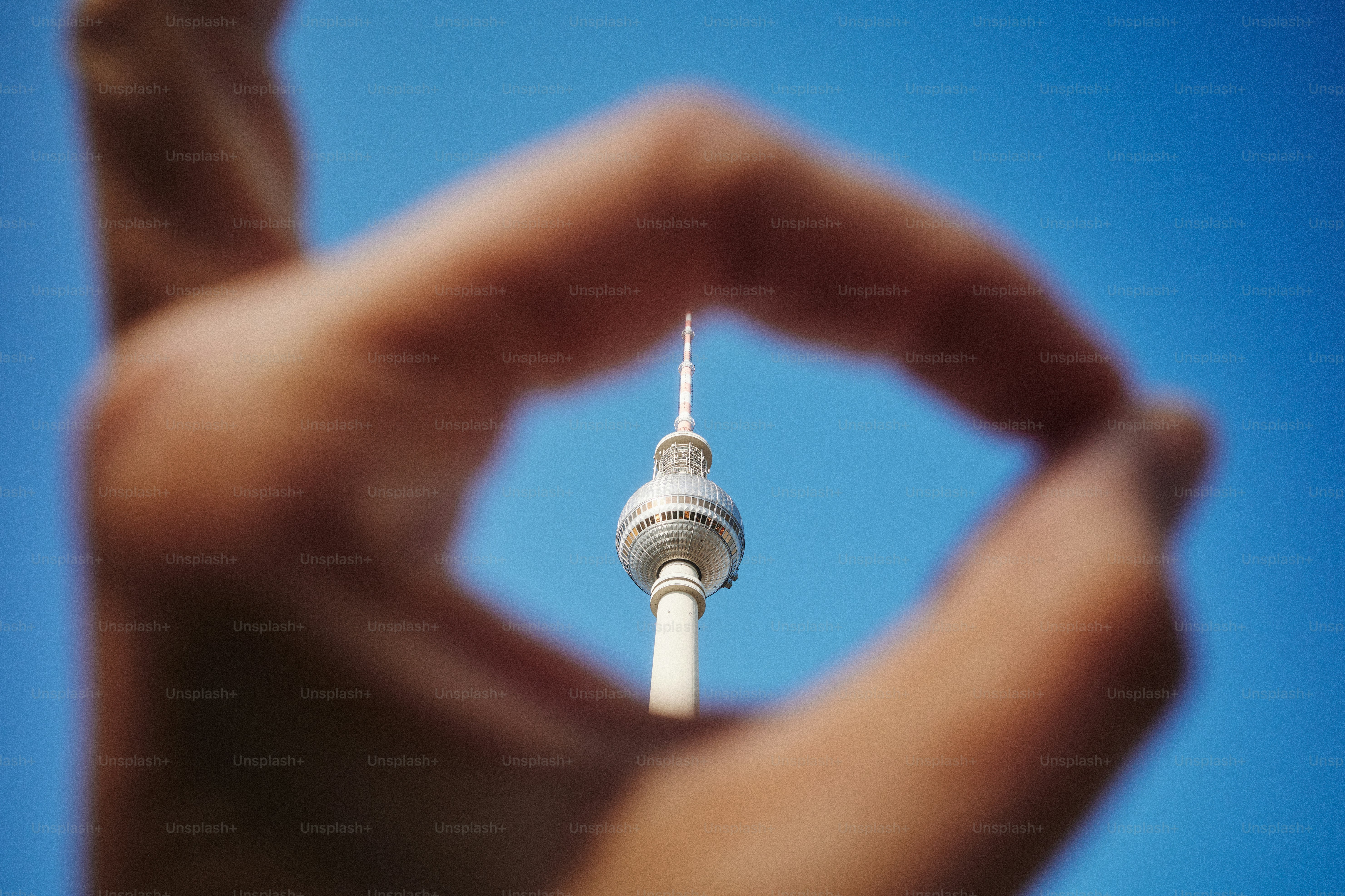 A hand frames the berlin television tower.