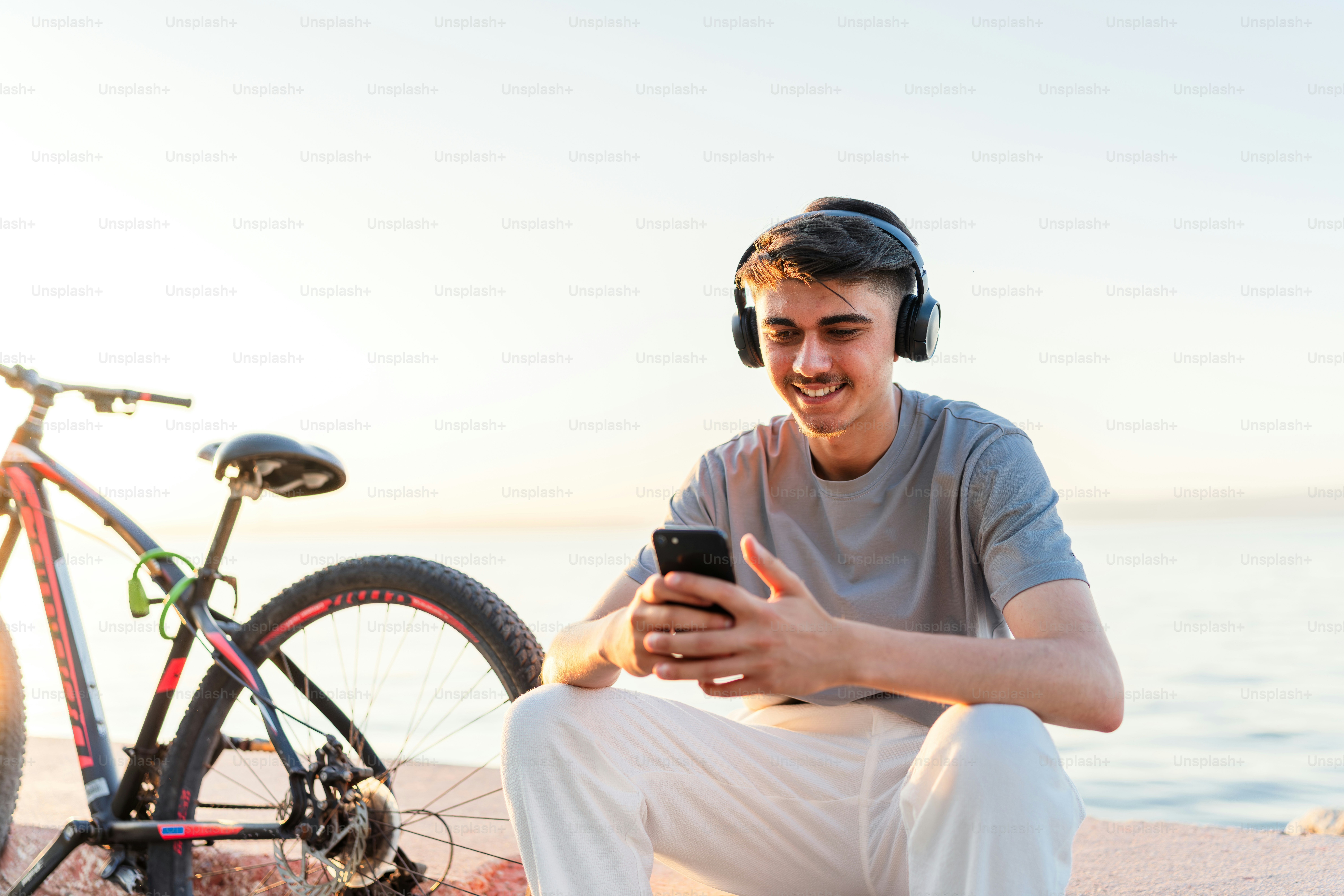 Hombre con auriculares usando su teléfono cerca de una bicicleta.