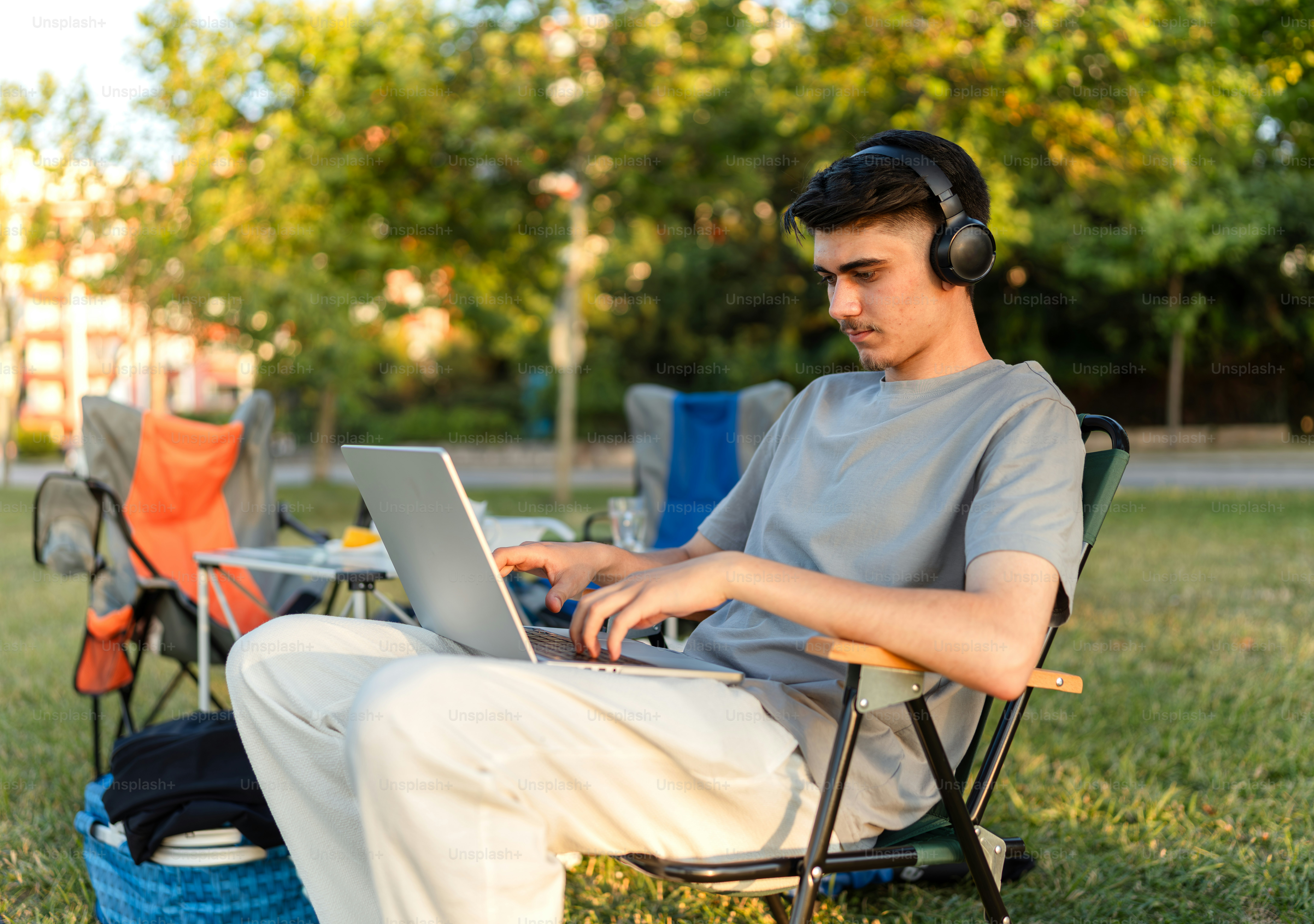 Man works on laptop in a park setting.