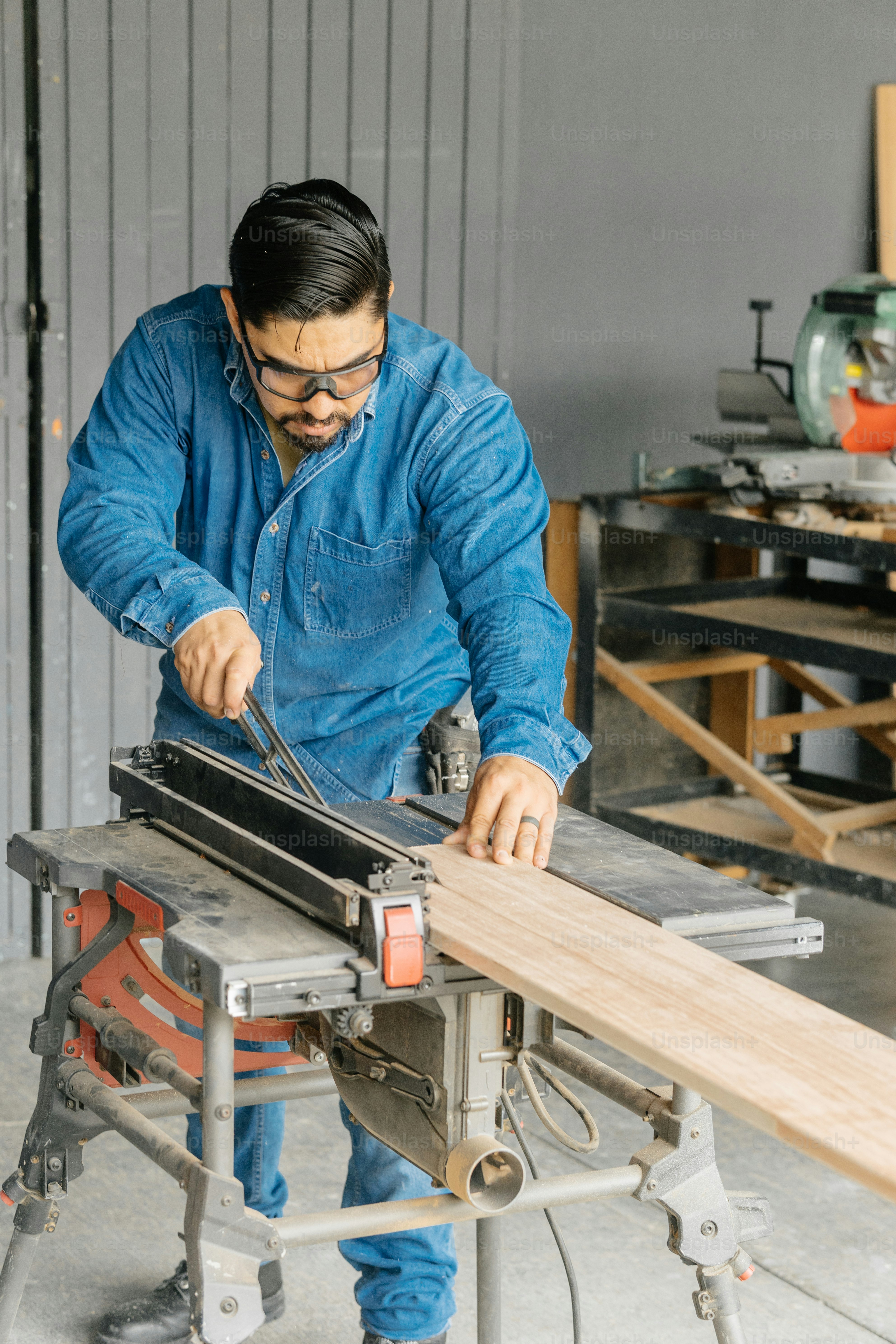 A carpenter is cutting wood with a saw.