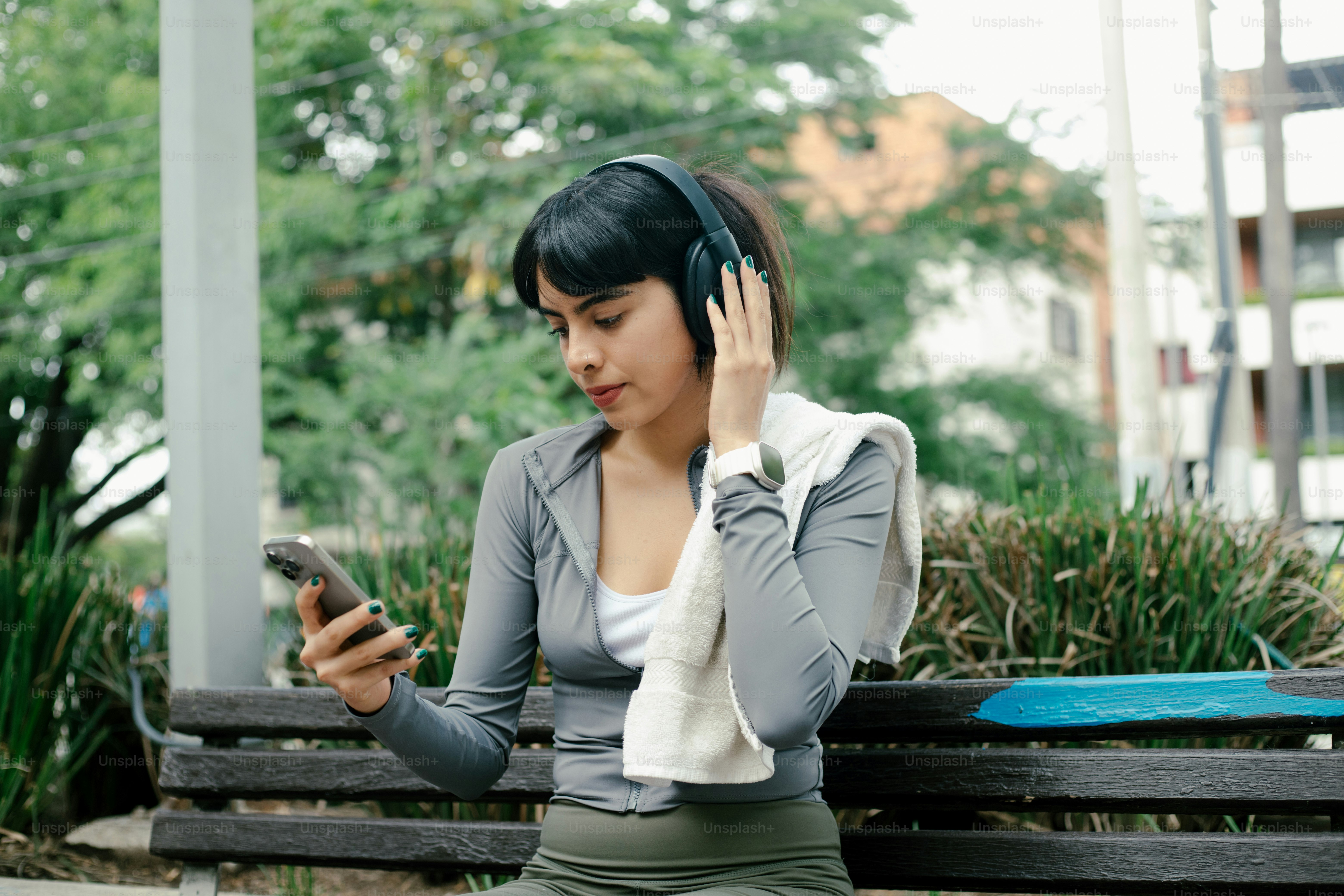 Woman selects music while wearing headphones outside.