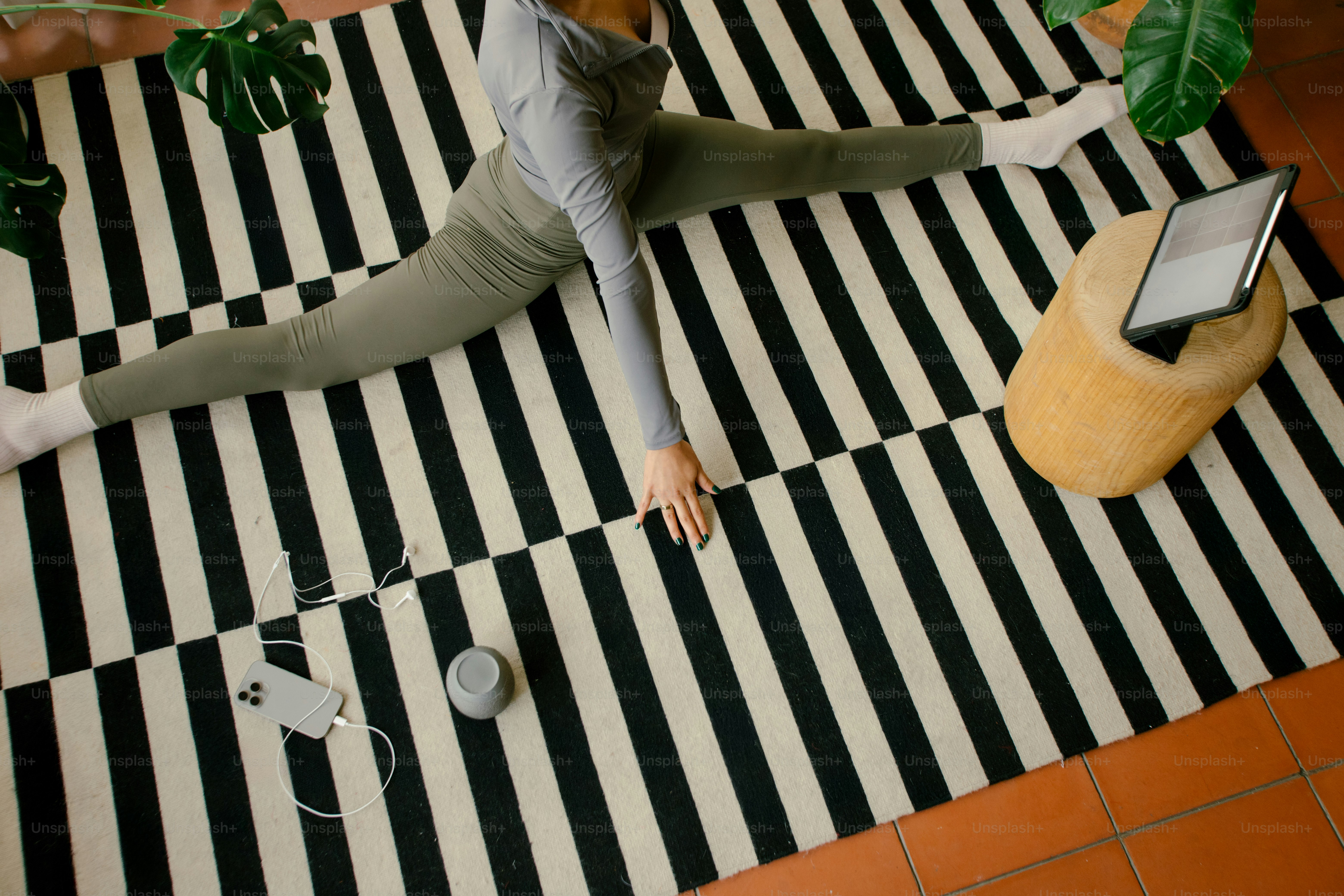 Woman does splits while watching a tablet.