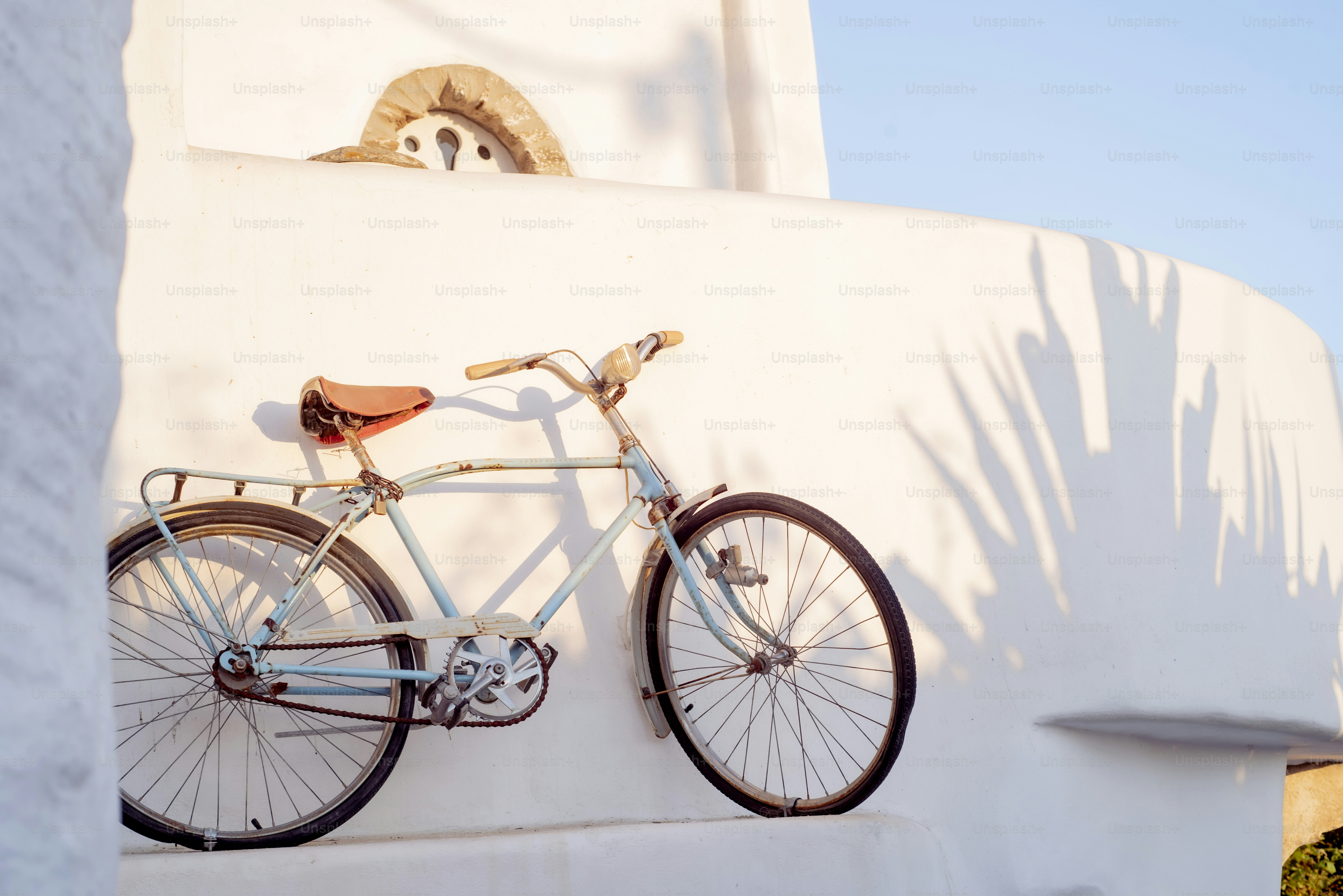 A bicycle hangs on a bright white wall.