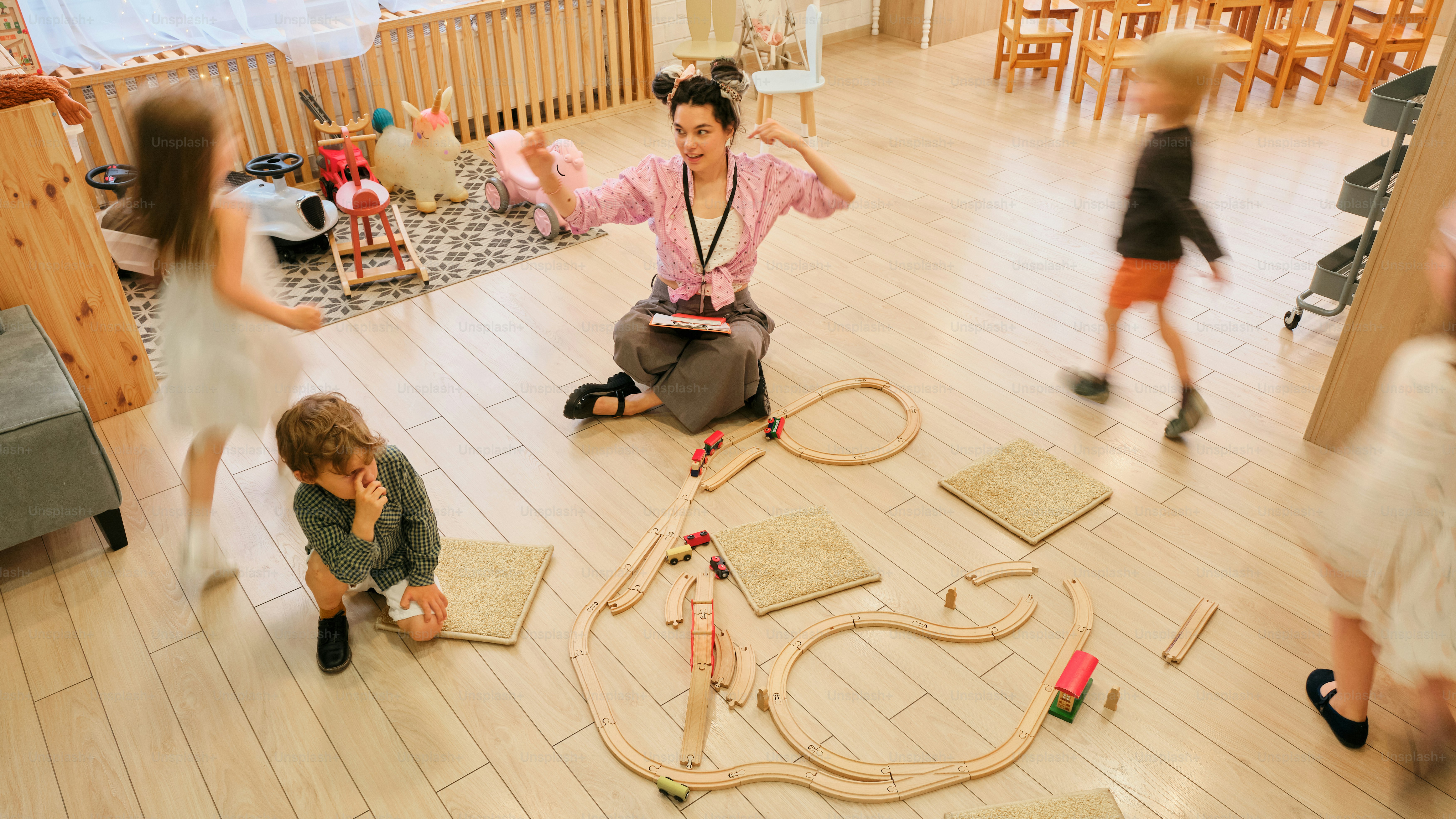 Ein Lehrer, umgeben von verspielten Kindern in einem Klassenzimmer.