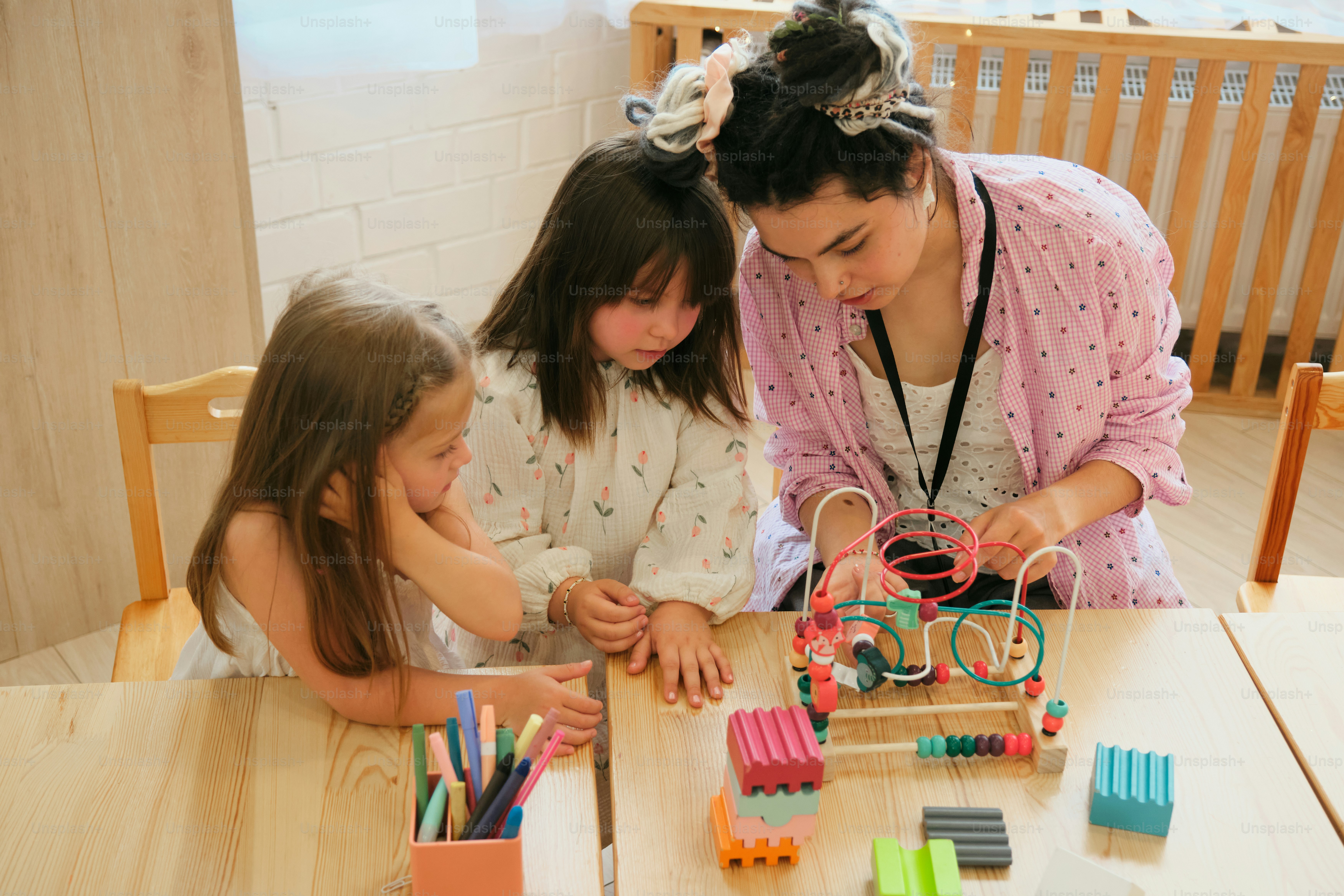 Die Kinder spielen und lernen gemeinsam mit einer Lehrkraft.