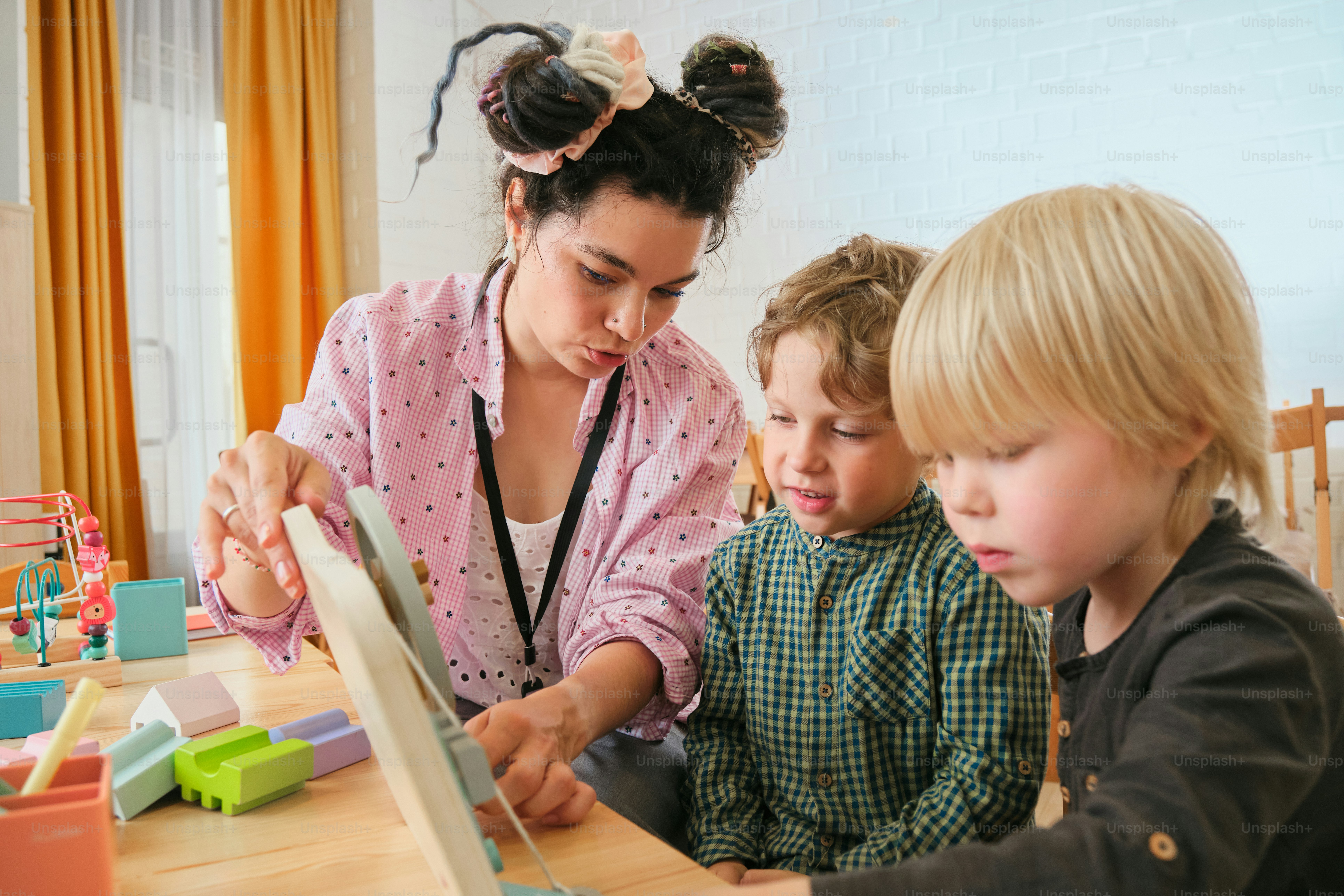 Der Lehrer hilft zwei kleinen Kindern bei einer Aktivität.
