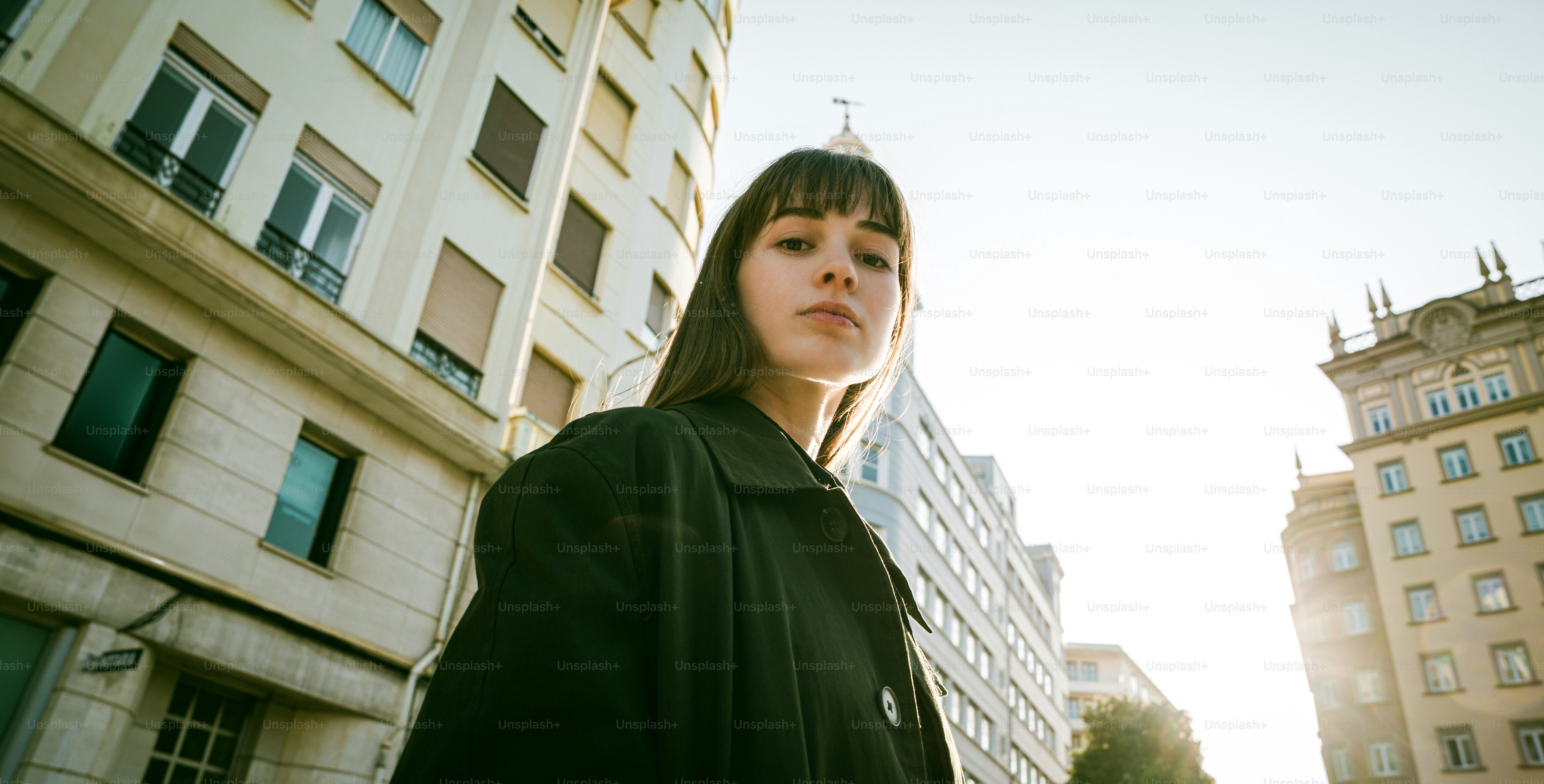 Una mujer está de pie en una ciudad mirando a la cámara.