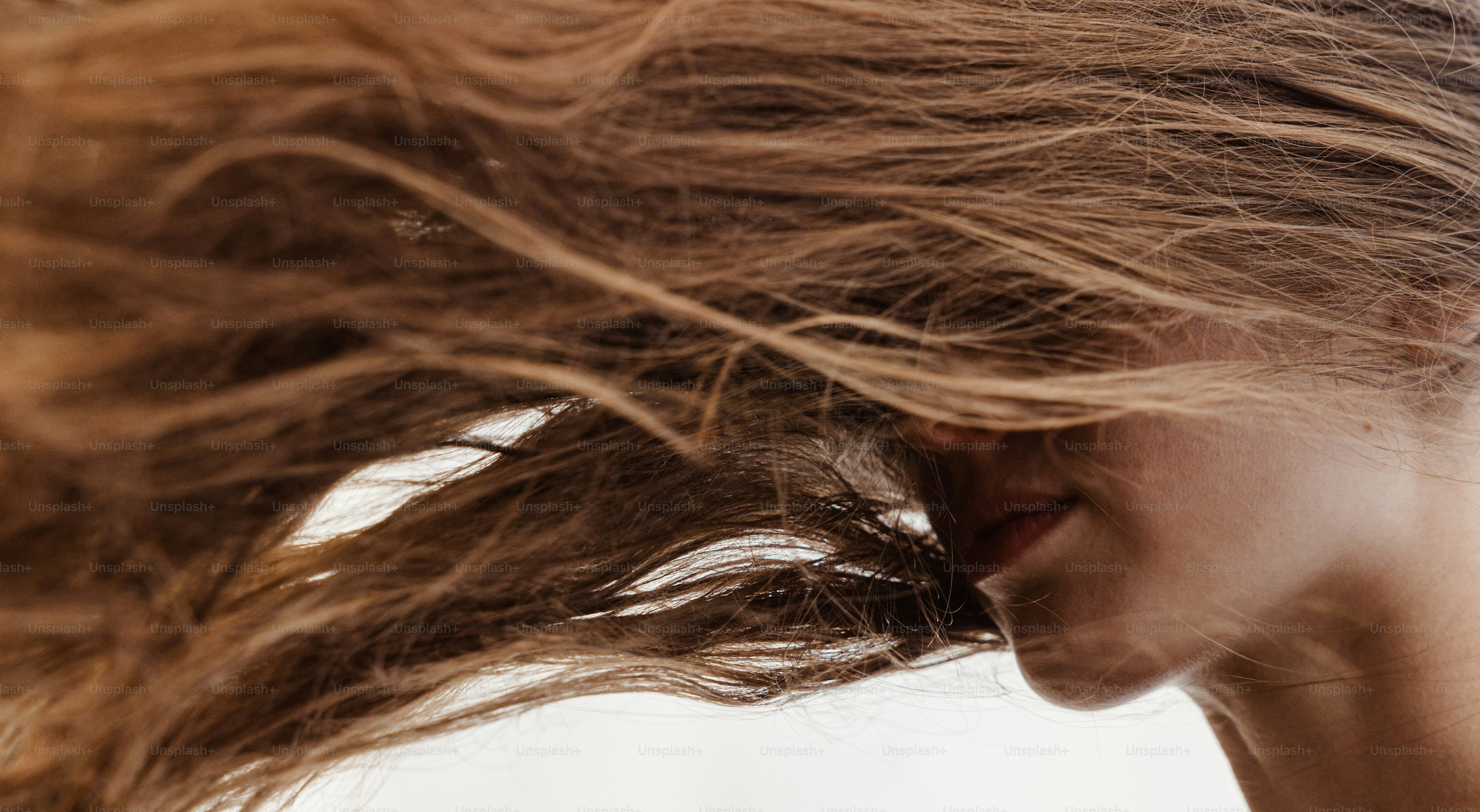 Fließendes braunes Haar verdeckt das Gesicht einer Frau.