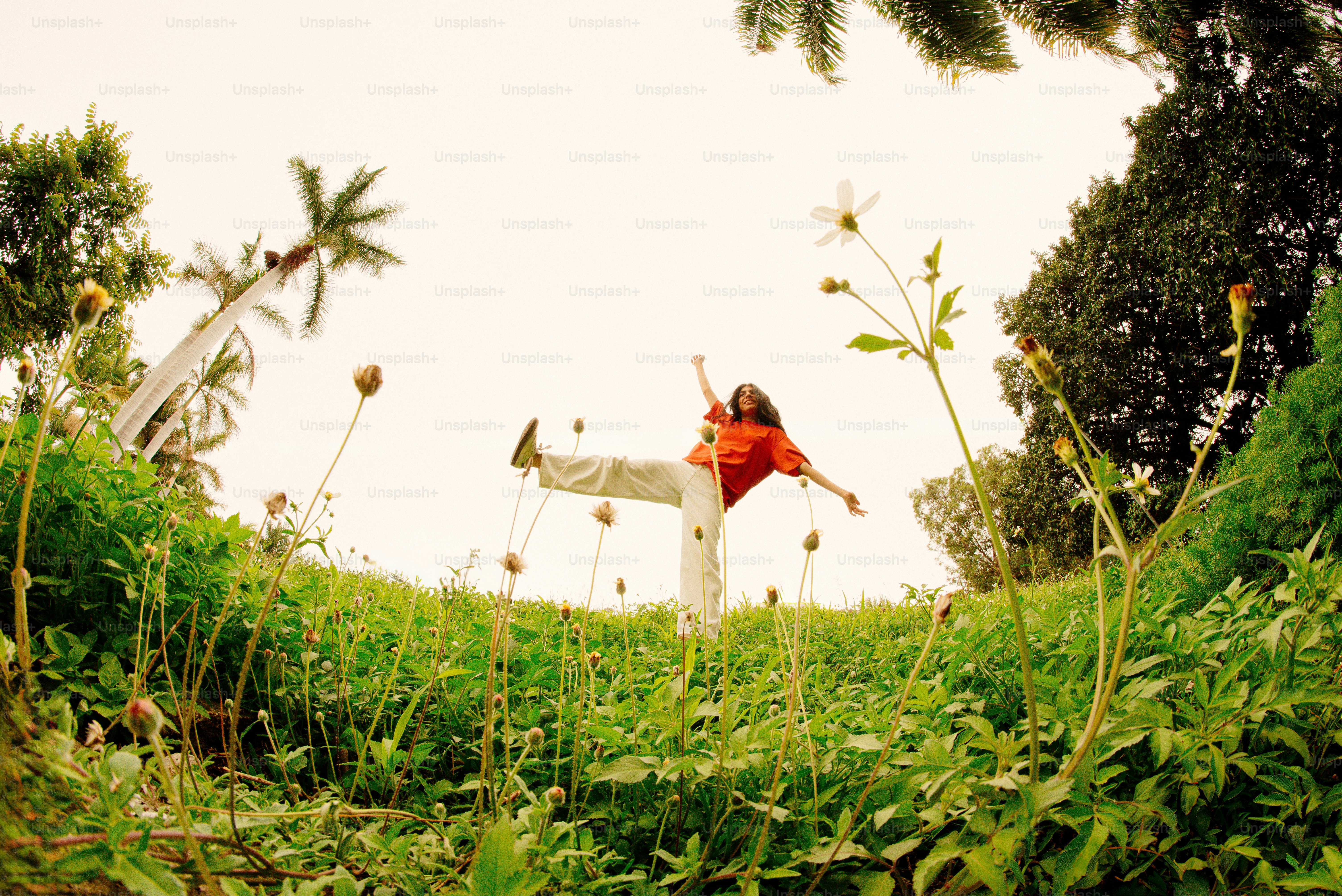 Man balances on a grassy hill with trees.