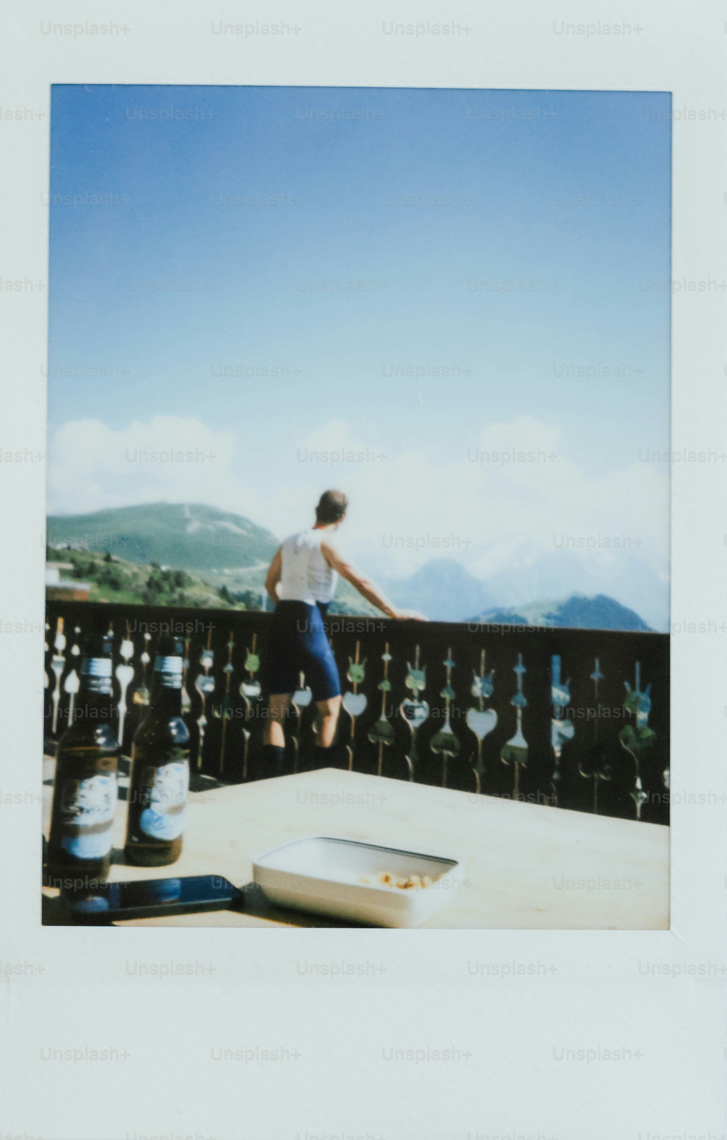 Person gazes at a mountain view from a balcony.