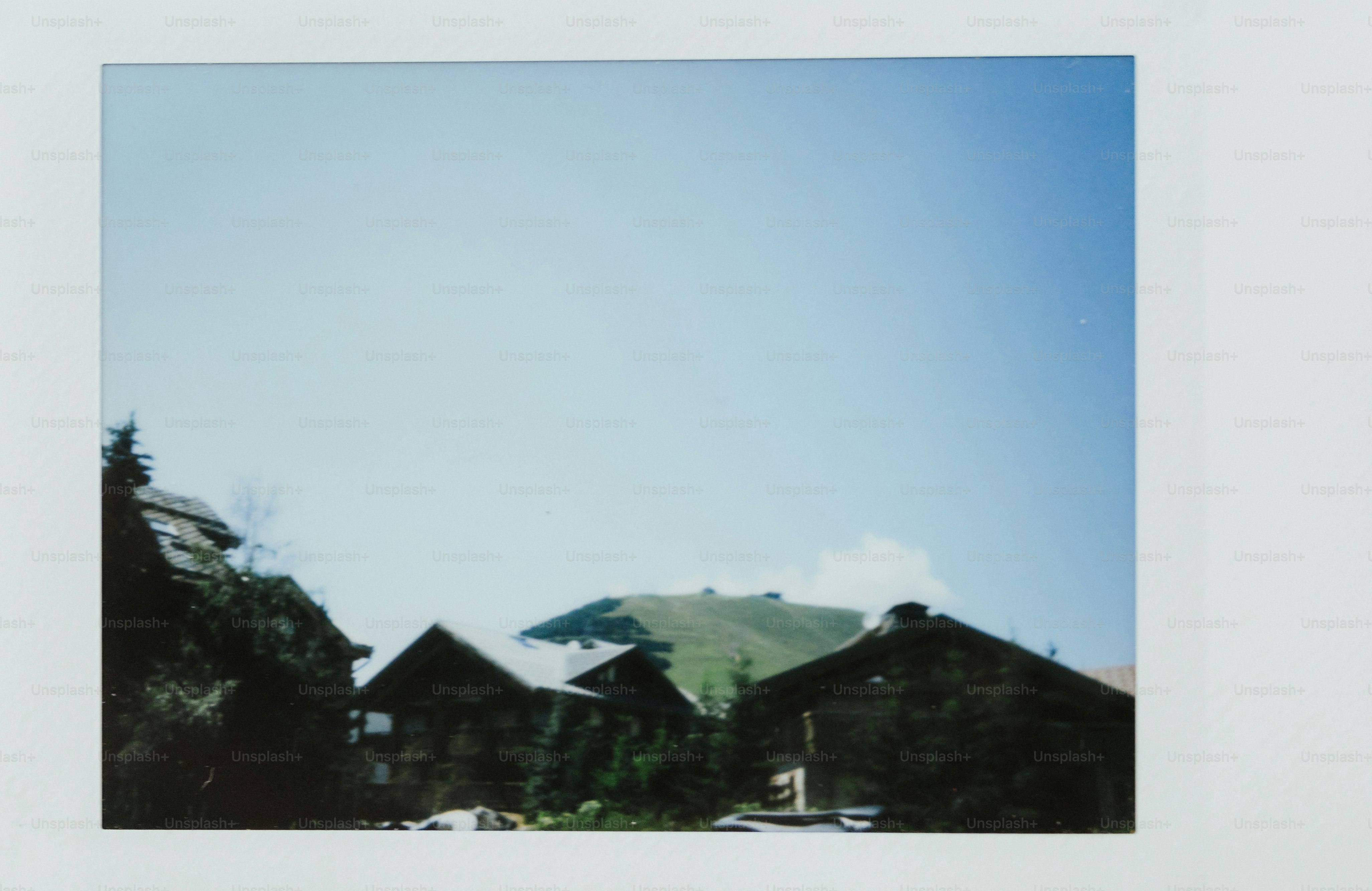 Huts are nestled against mountains under a blue sky.