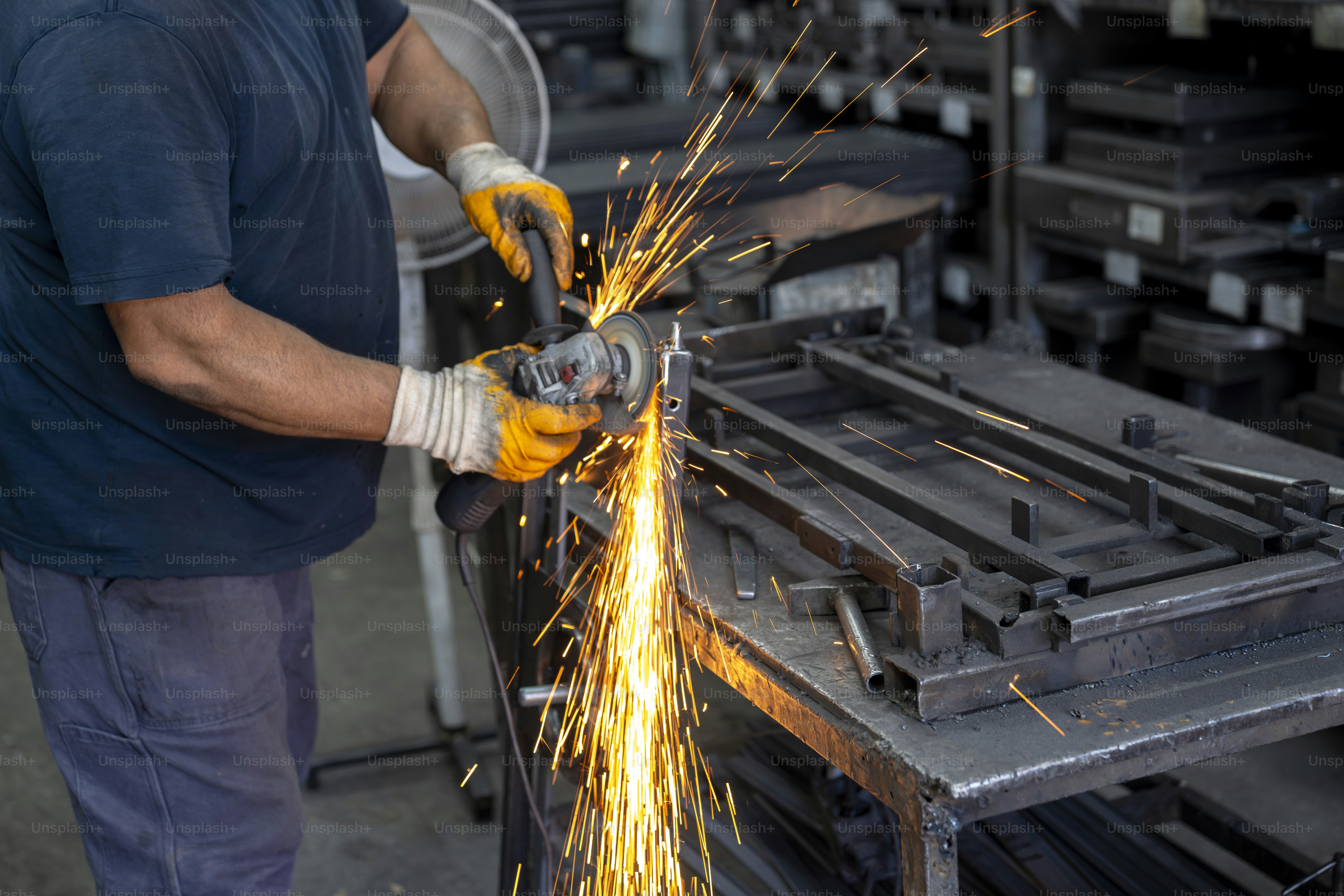 Um trabalhador usa uma rebarbadora, criando faíscas.