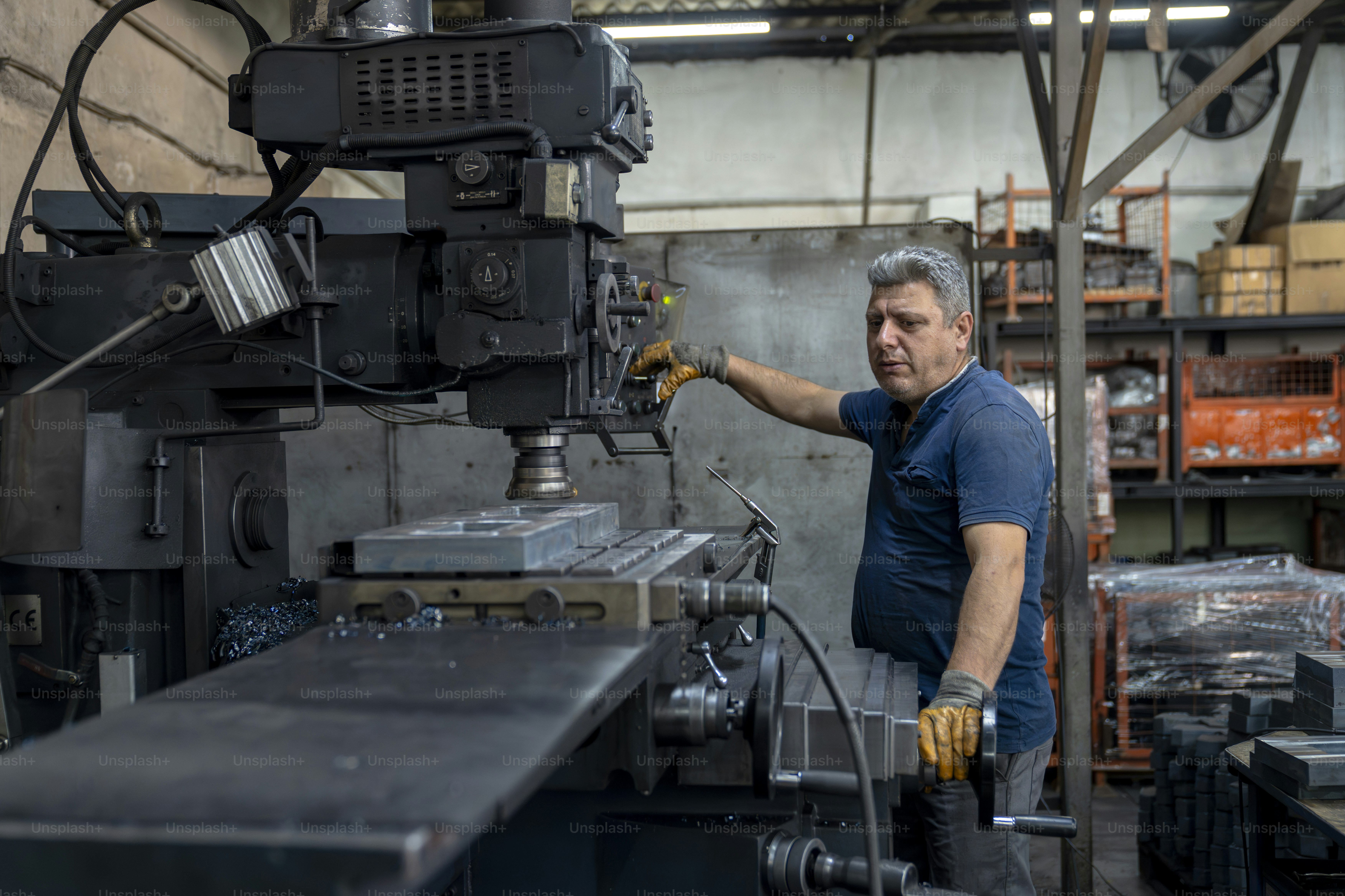 Um trabalhador opera uma grande fresadora industrial.