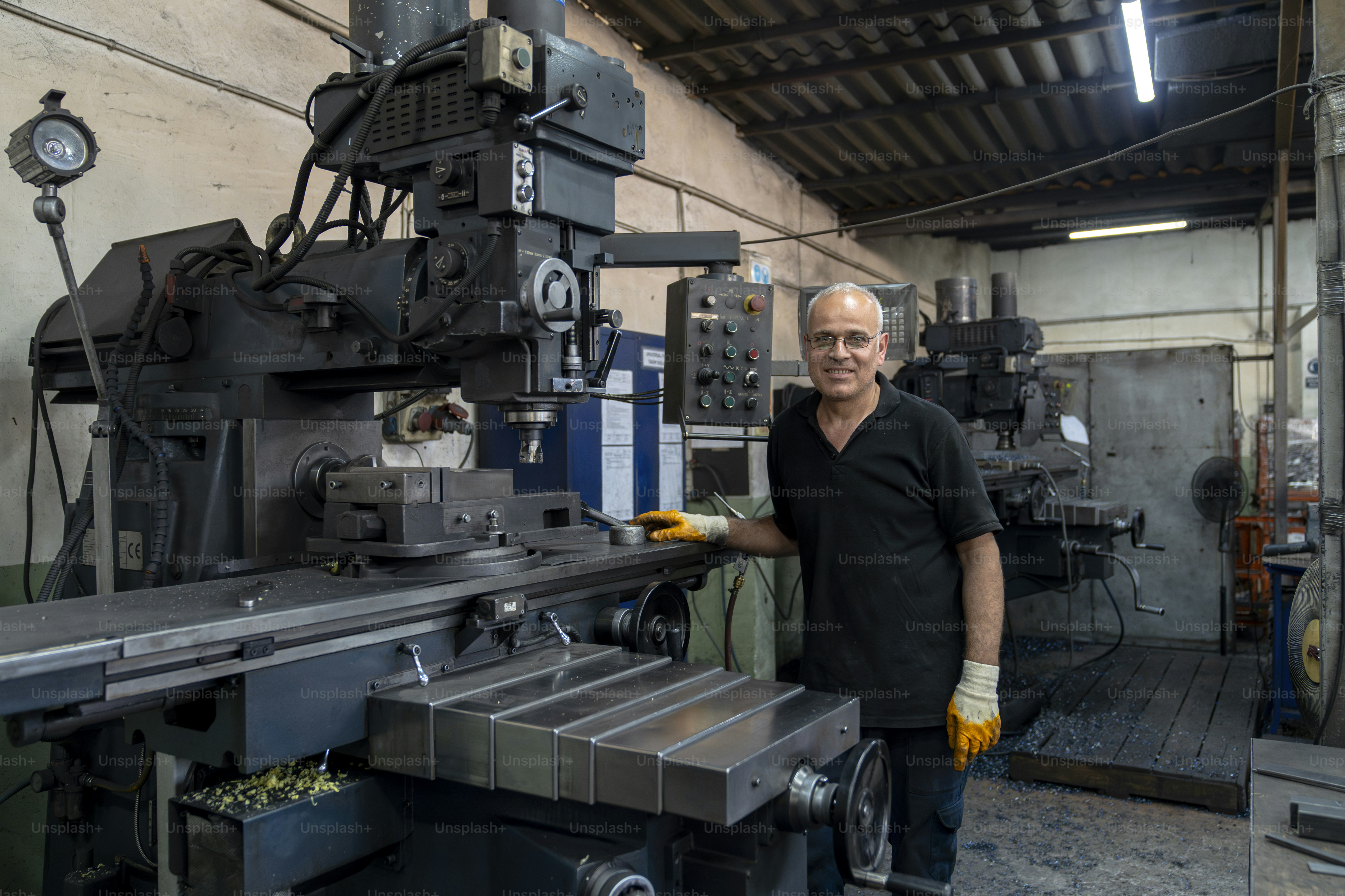 Um homem fica ao lado de máquinas em uma oficina.