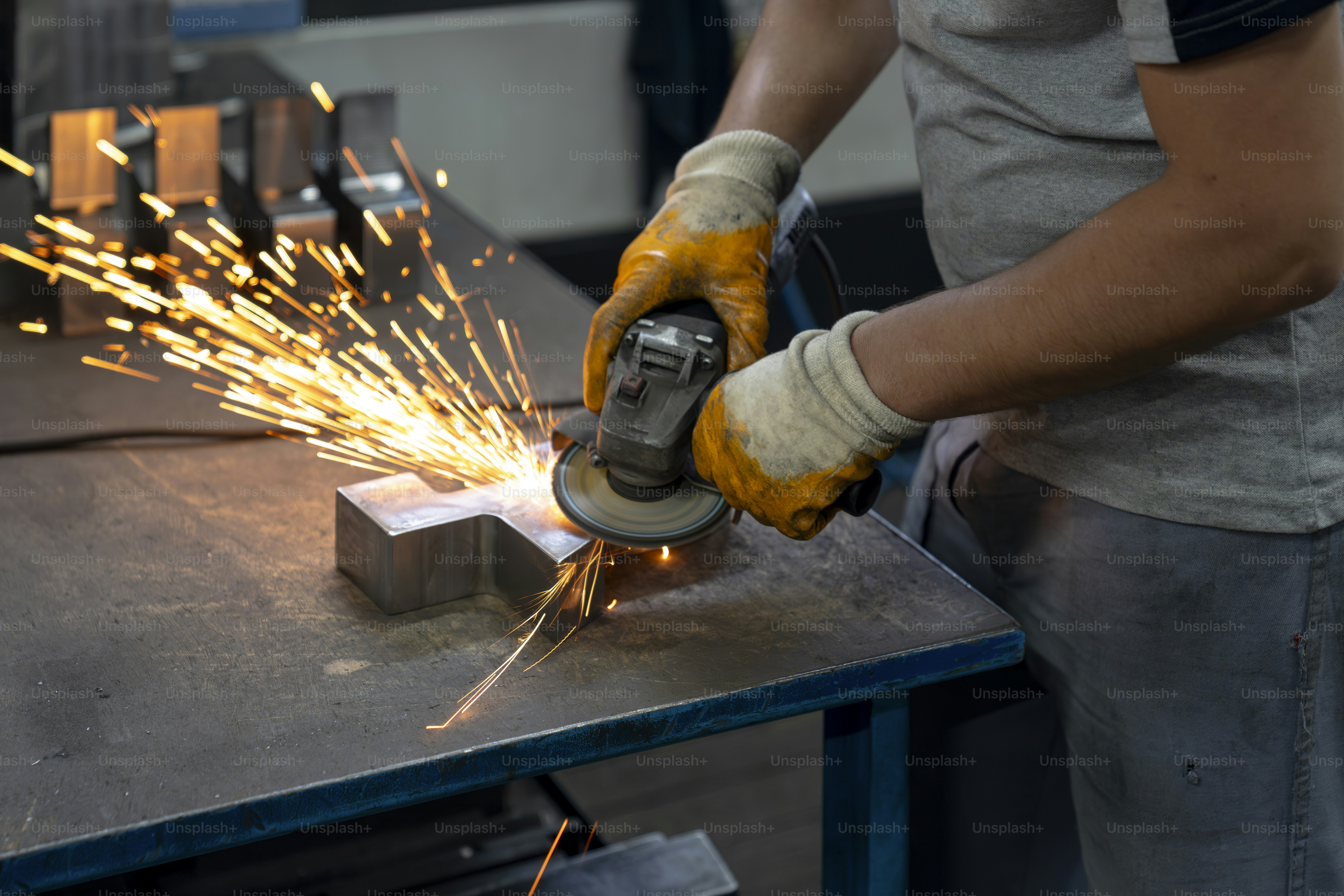 Um trabalhador usa um moedor, criando faíscas.