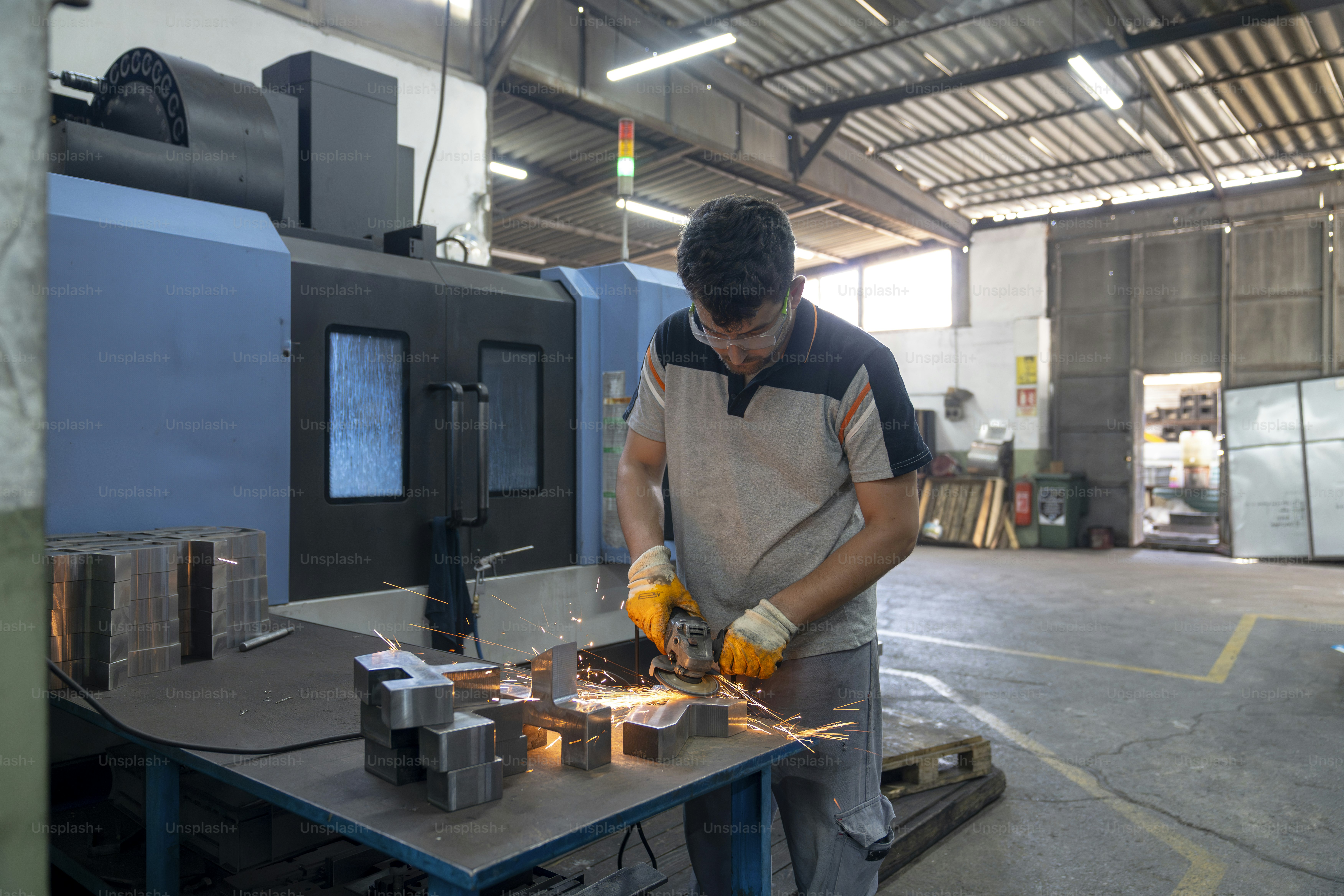 Um homem está usando um moedor em uma fábrica.