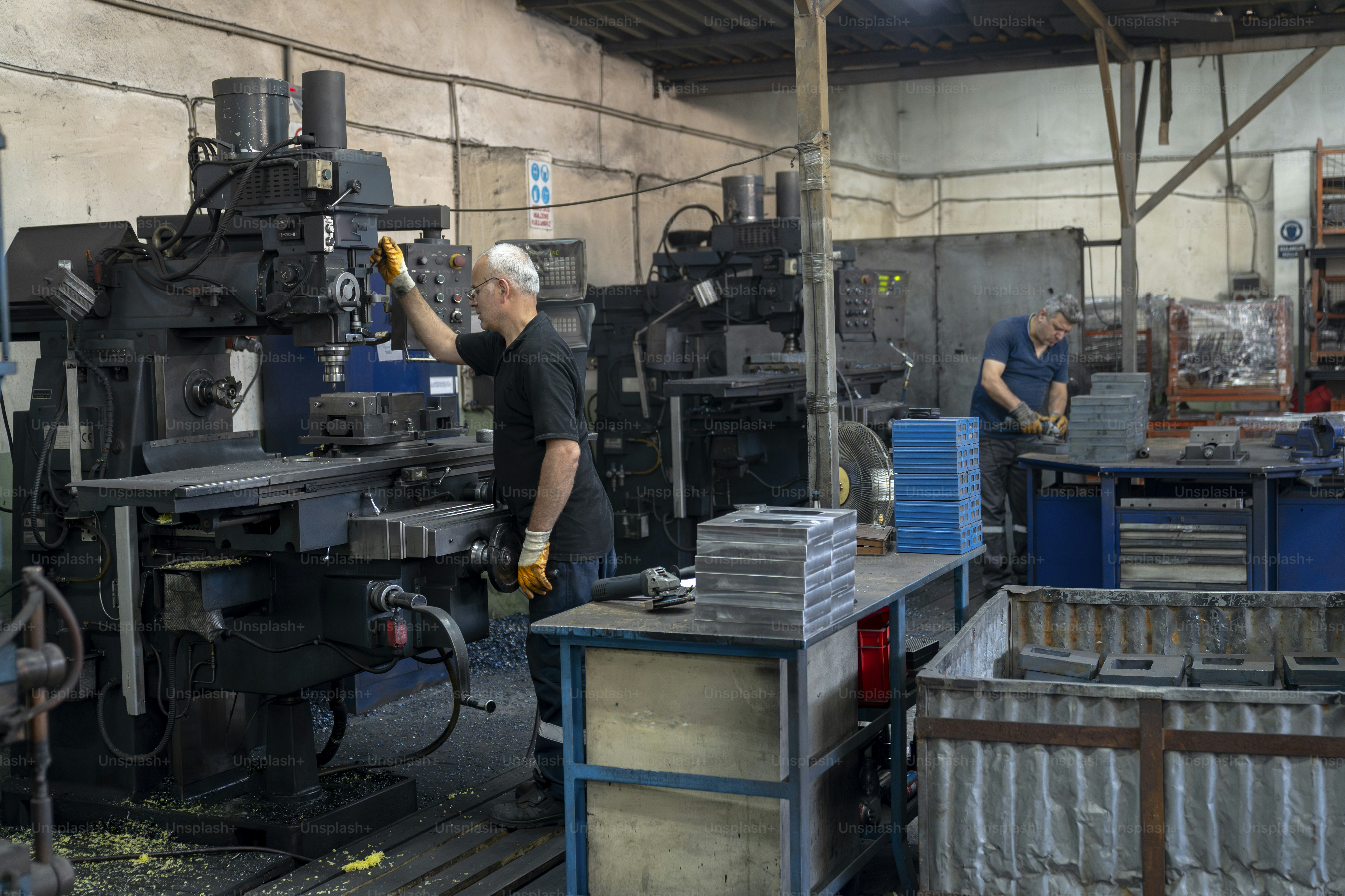 Os trabalhadores operam máquinas em uma oficina de metal.