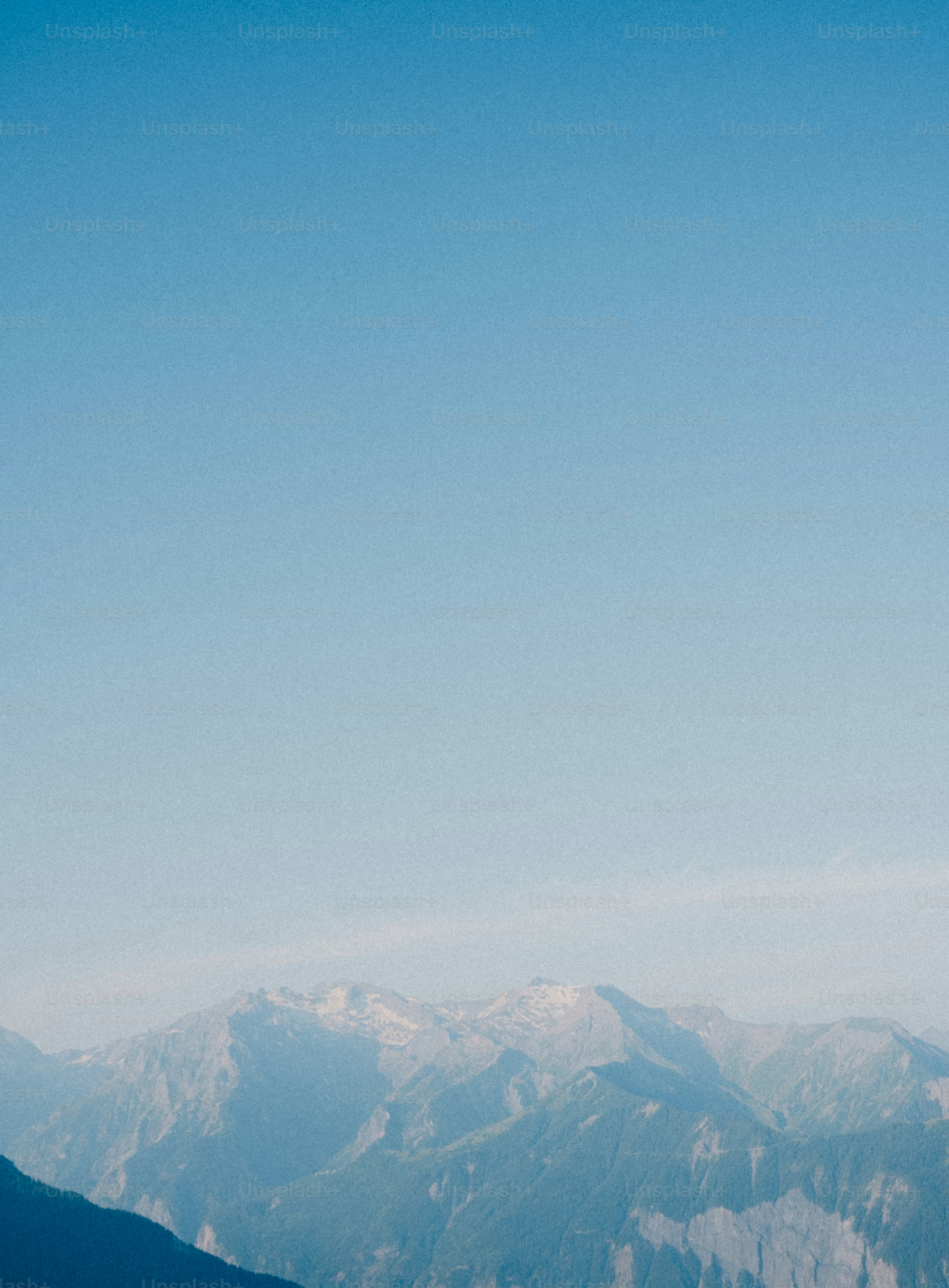 Mountains sit under a vast, clear blue sky.