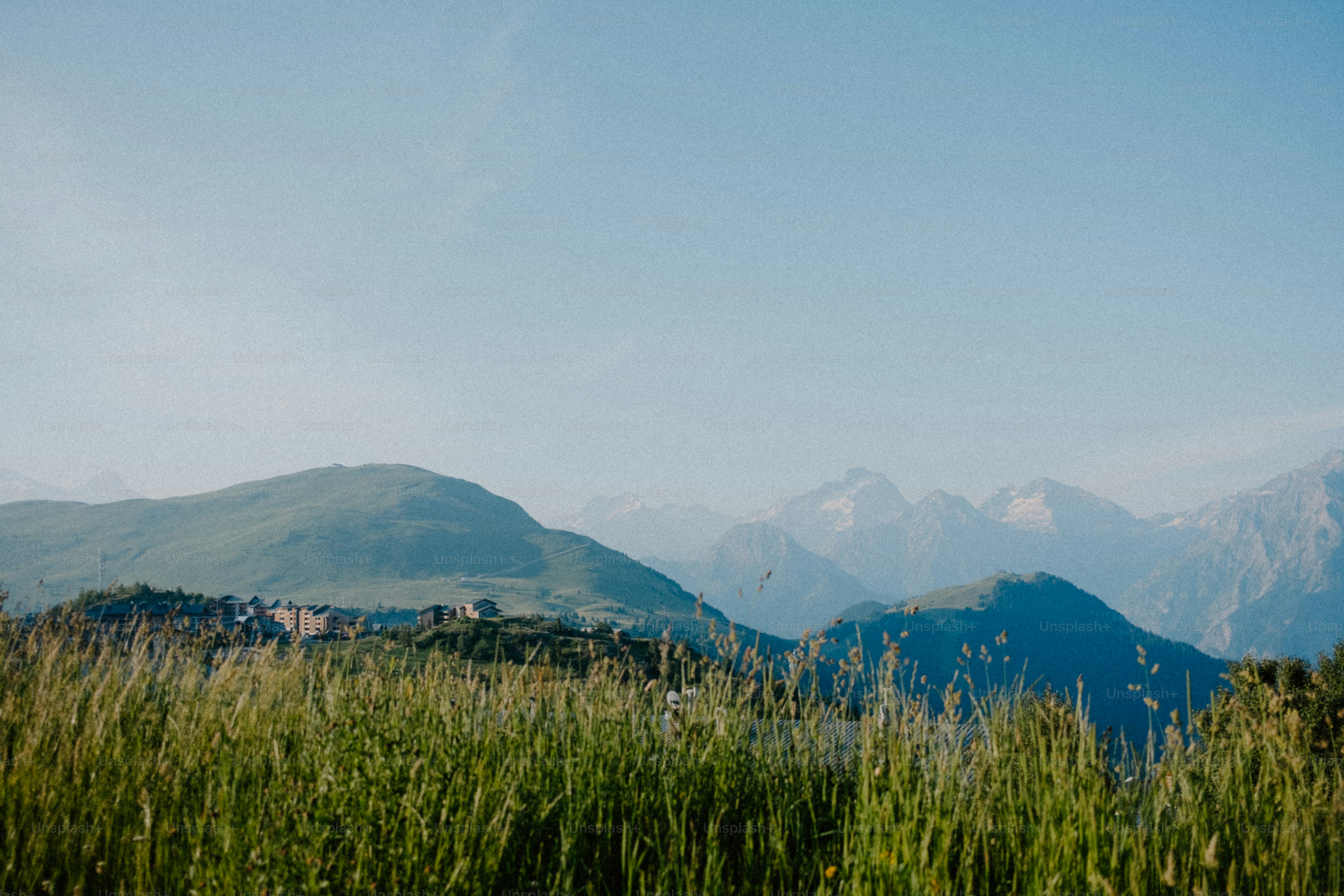 Mountains rise above green fields and blue sky.