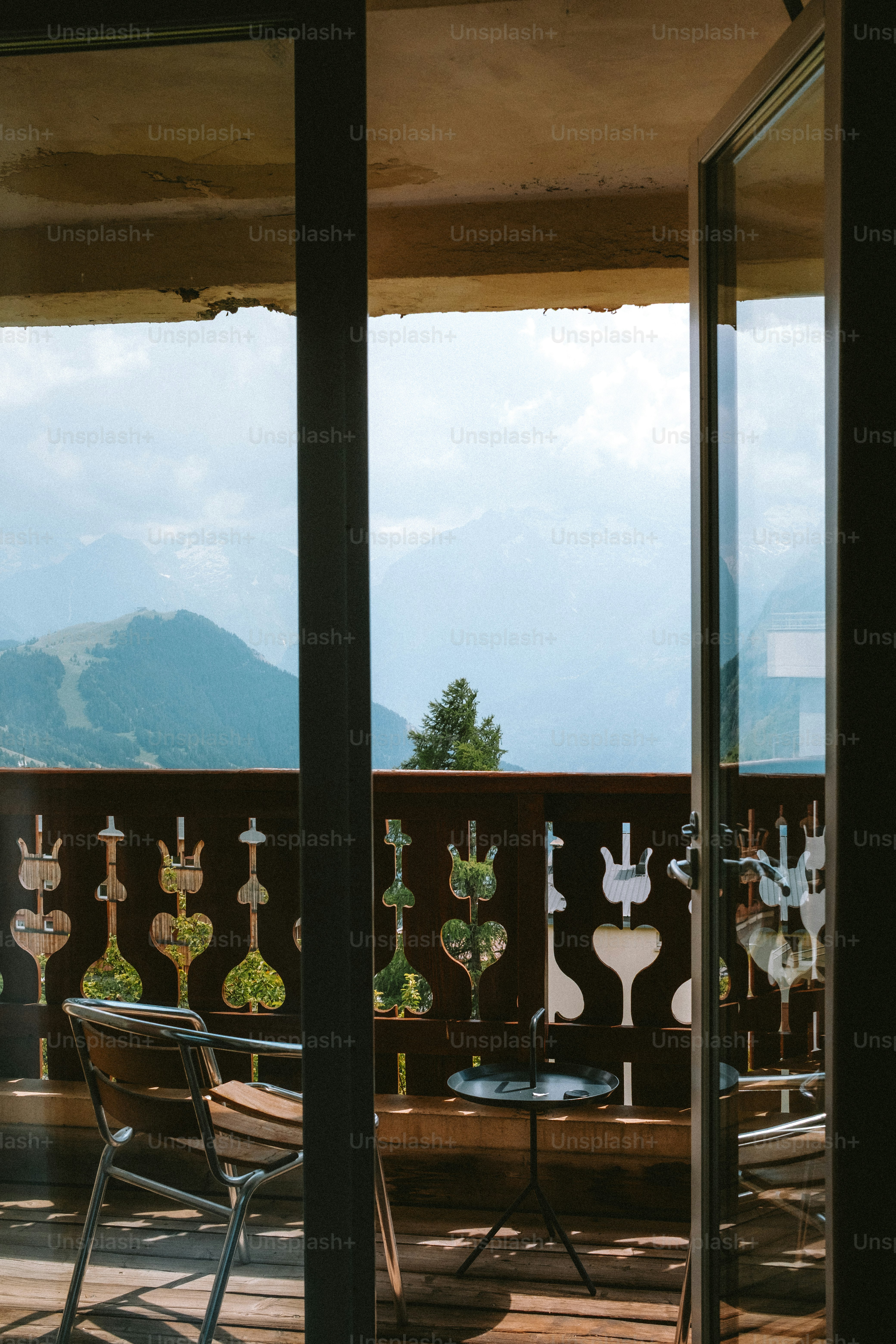 A balcony view of mountains through an open door.