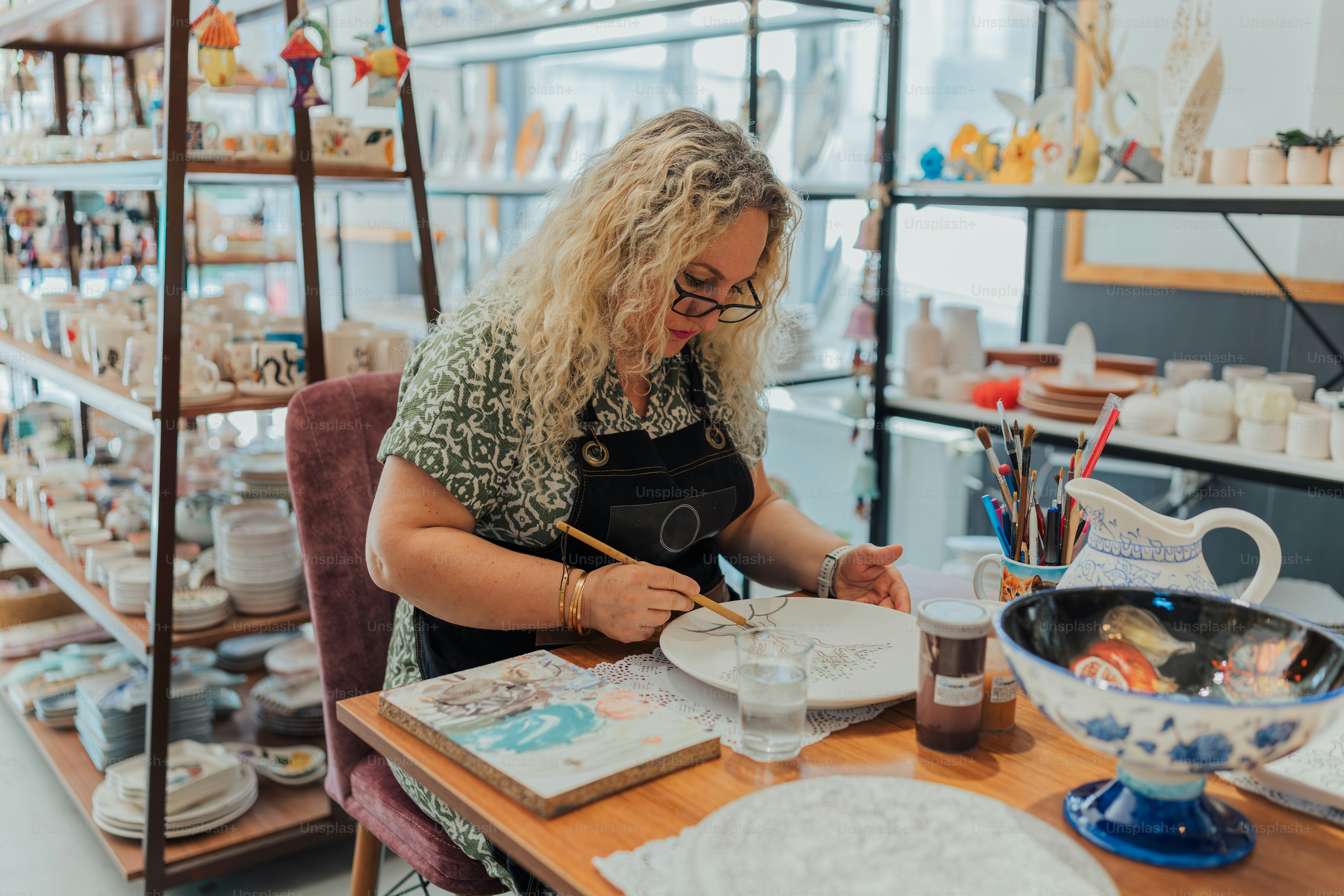 Woman paints a plate in a ceramic studio.