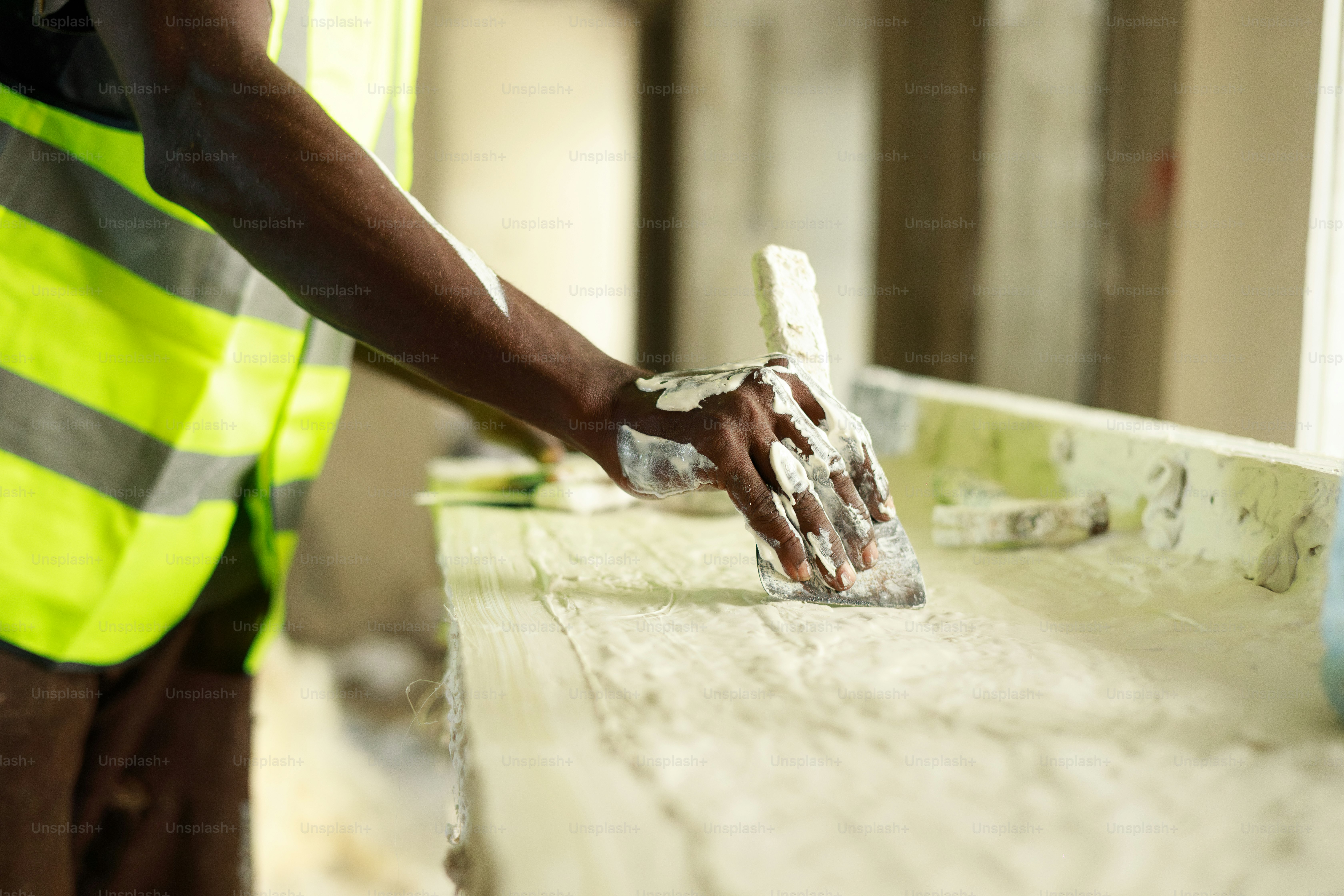 A worker is applying plaster with a trowel. photo – Construction Image ...