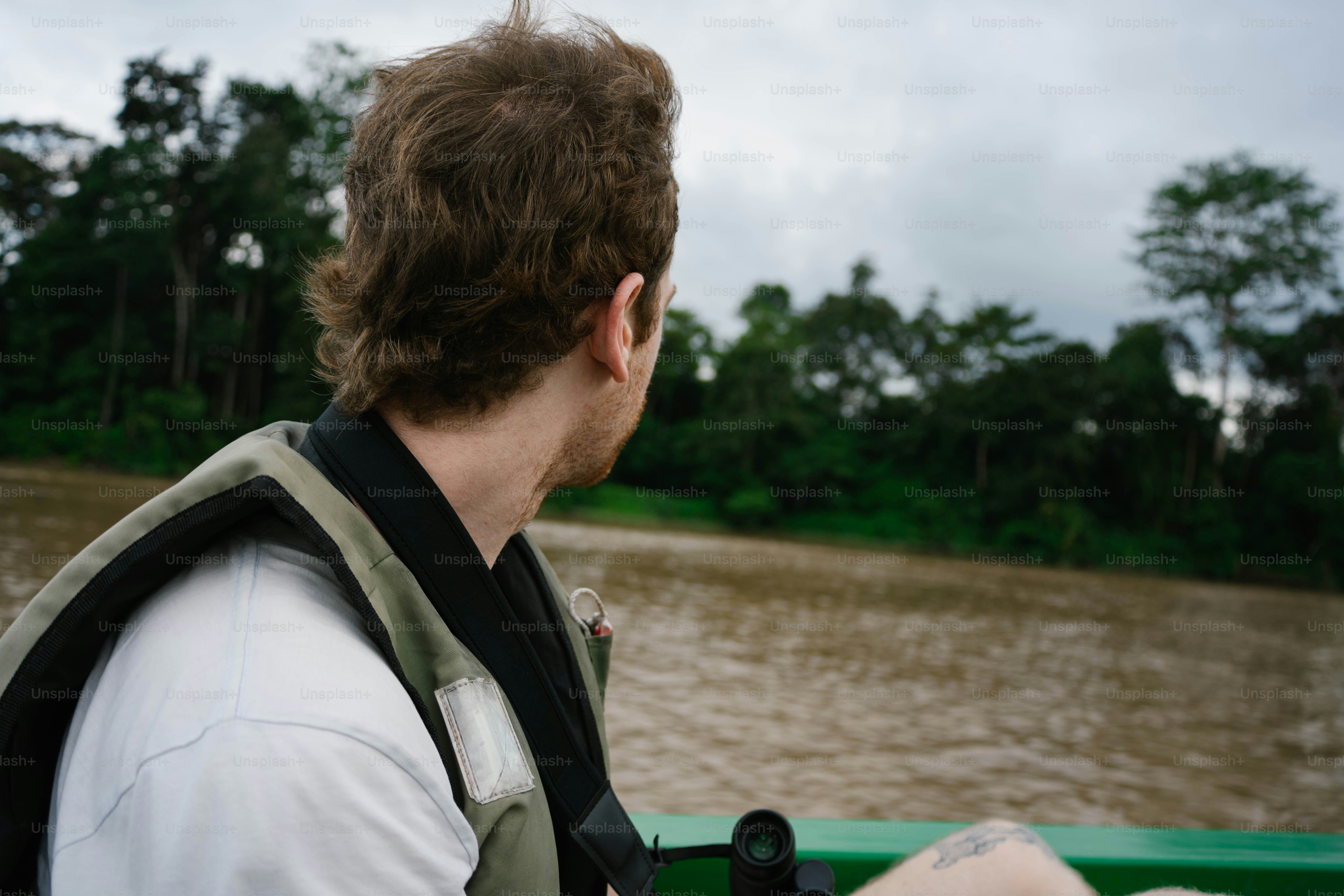 Man in boat looks at the lush riverside landscape. photo – Travel Image ...