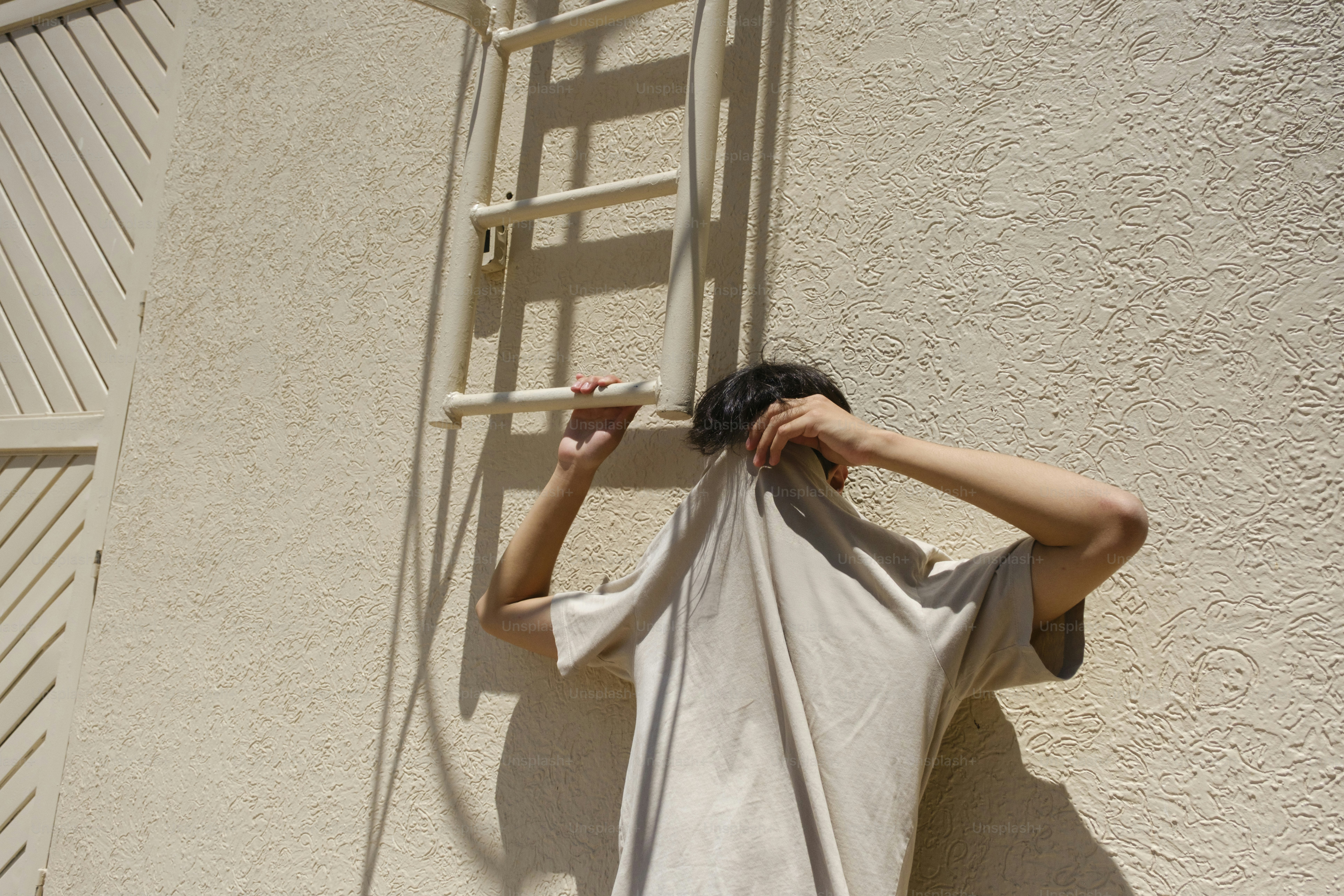 壁のTシャツの後ろに隠れている人。