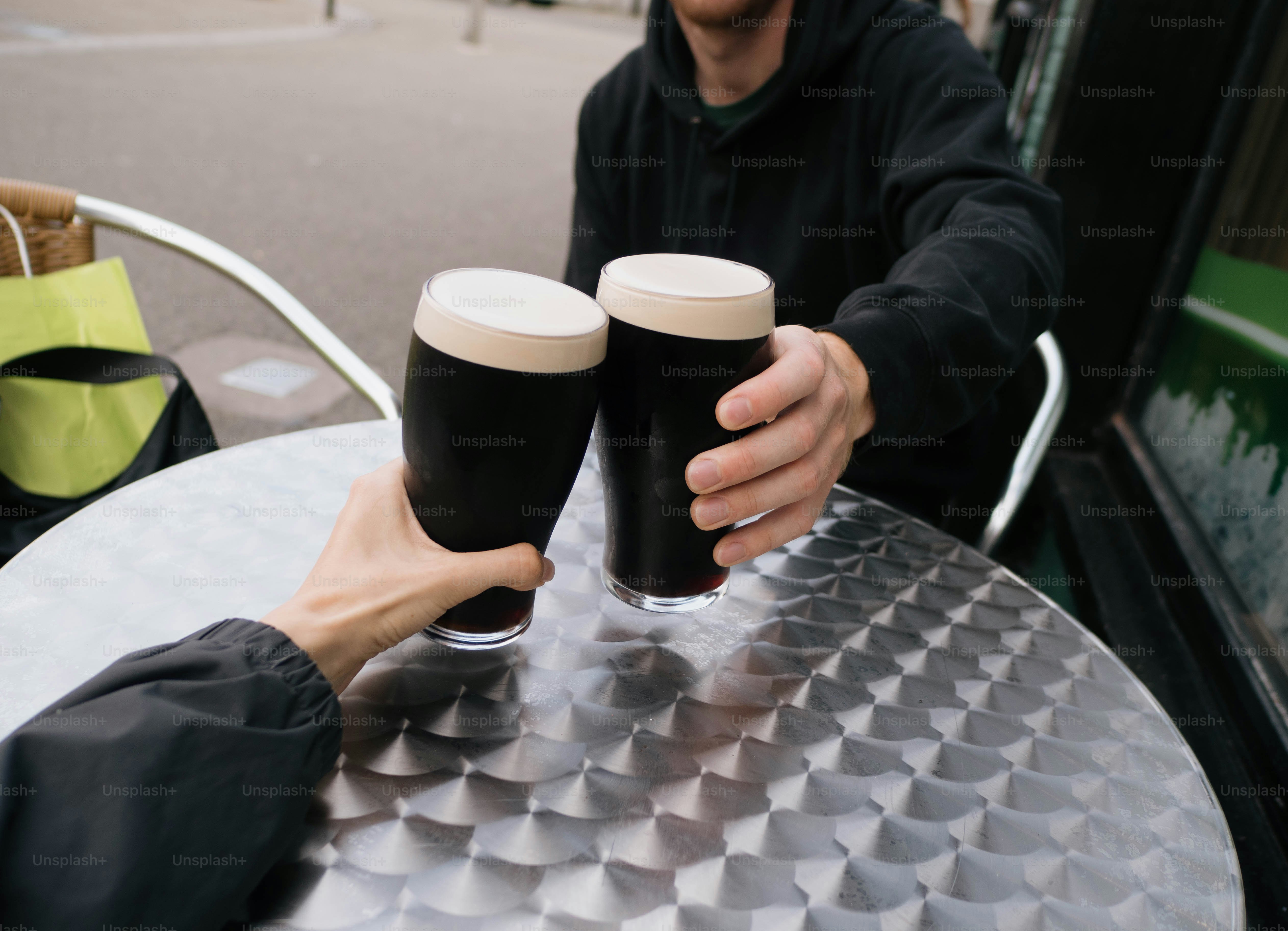 Two people cheersing pints of stout. photo – Beer Image on Unsplash