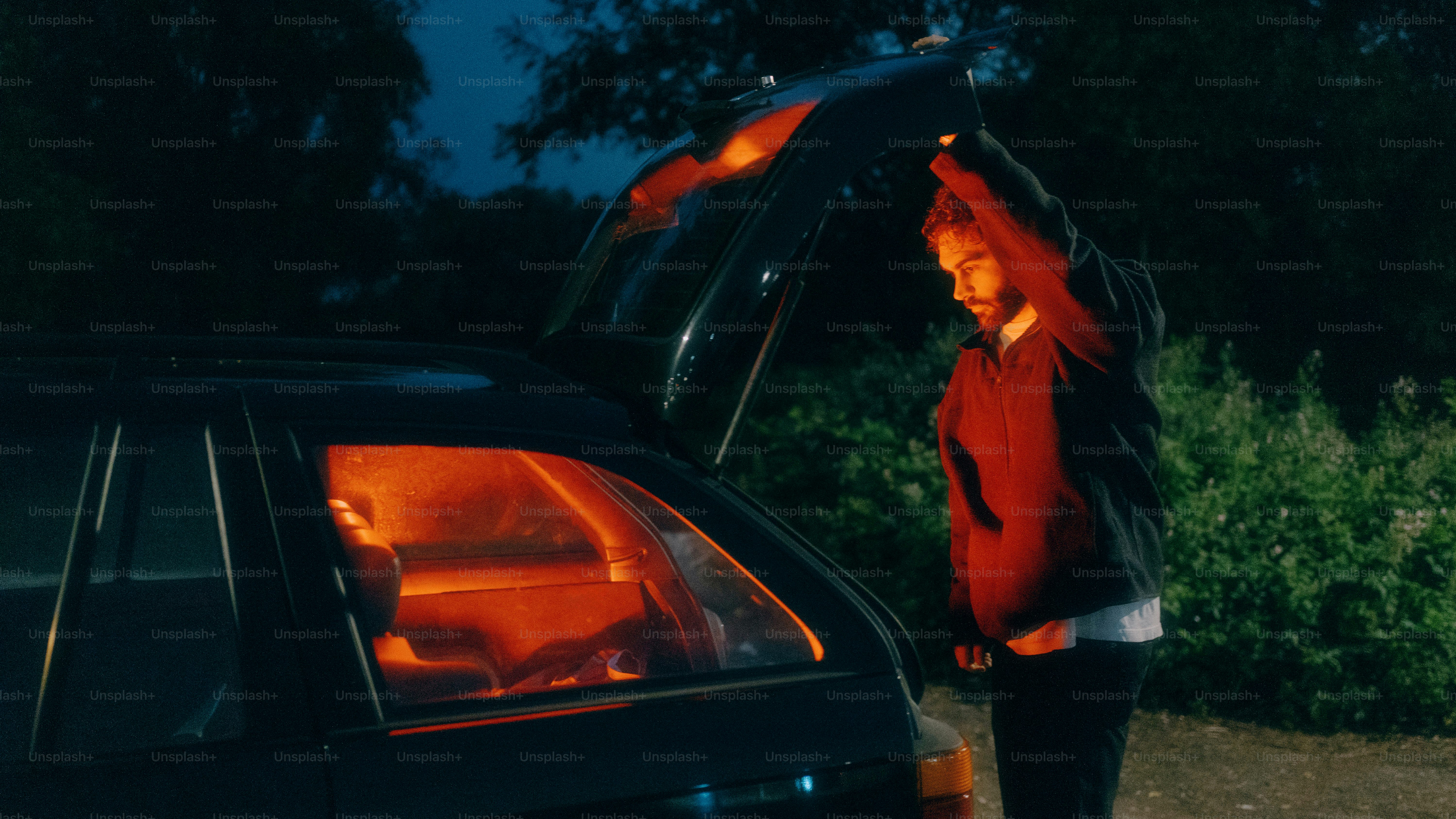 Una persona sta aprendo il bagagliaio dell'auto di notte.