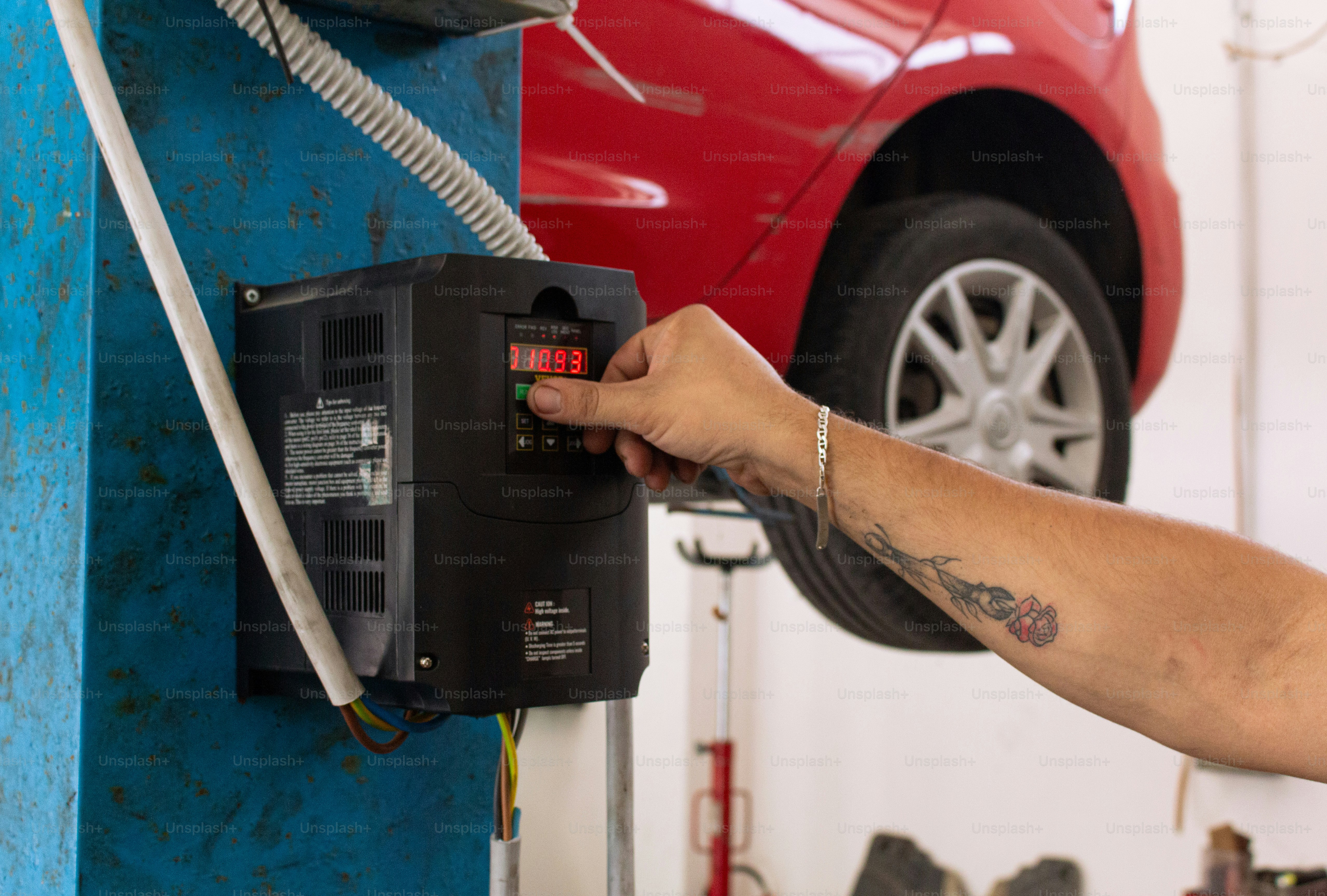 A mechanic adjusting a machine in a garage. photo – Worker Image on ...