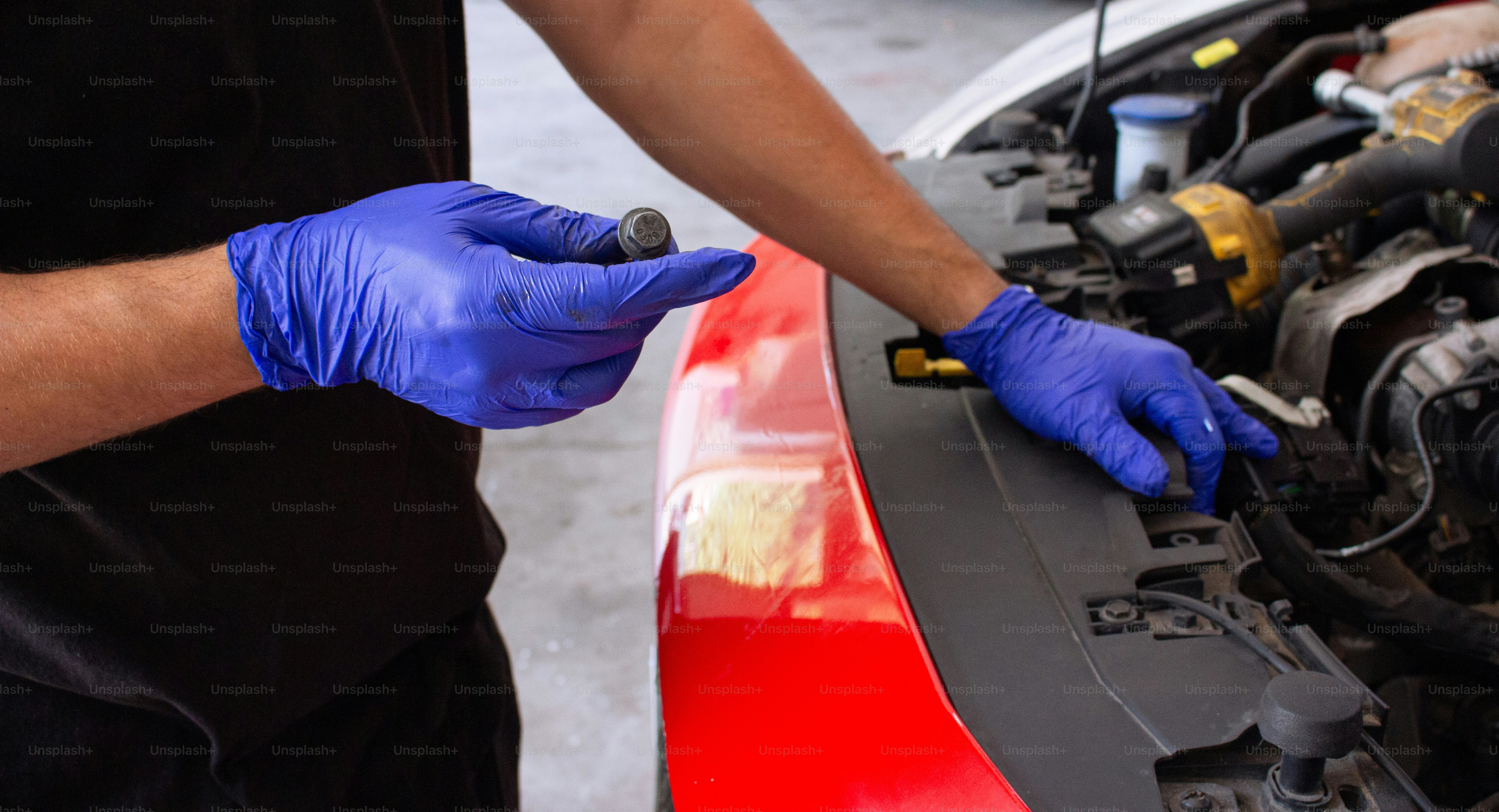 Mechanic working on a car engine wearing blue gloves. photo – Mechanic ...