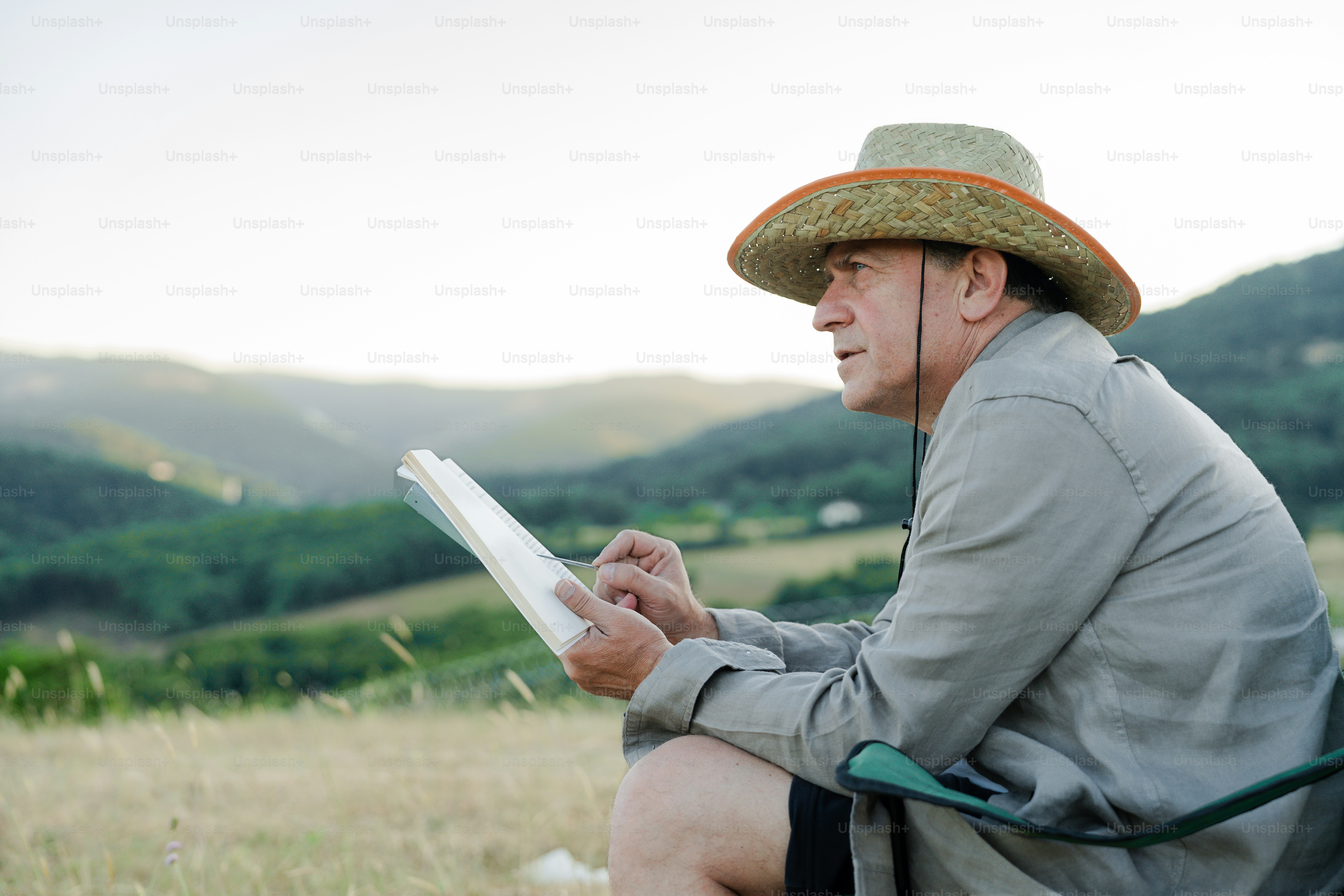 A man in a hat studies a paper outdoors.