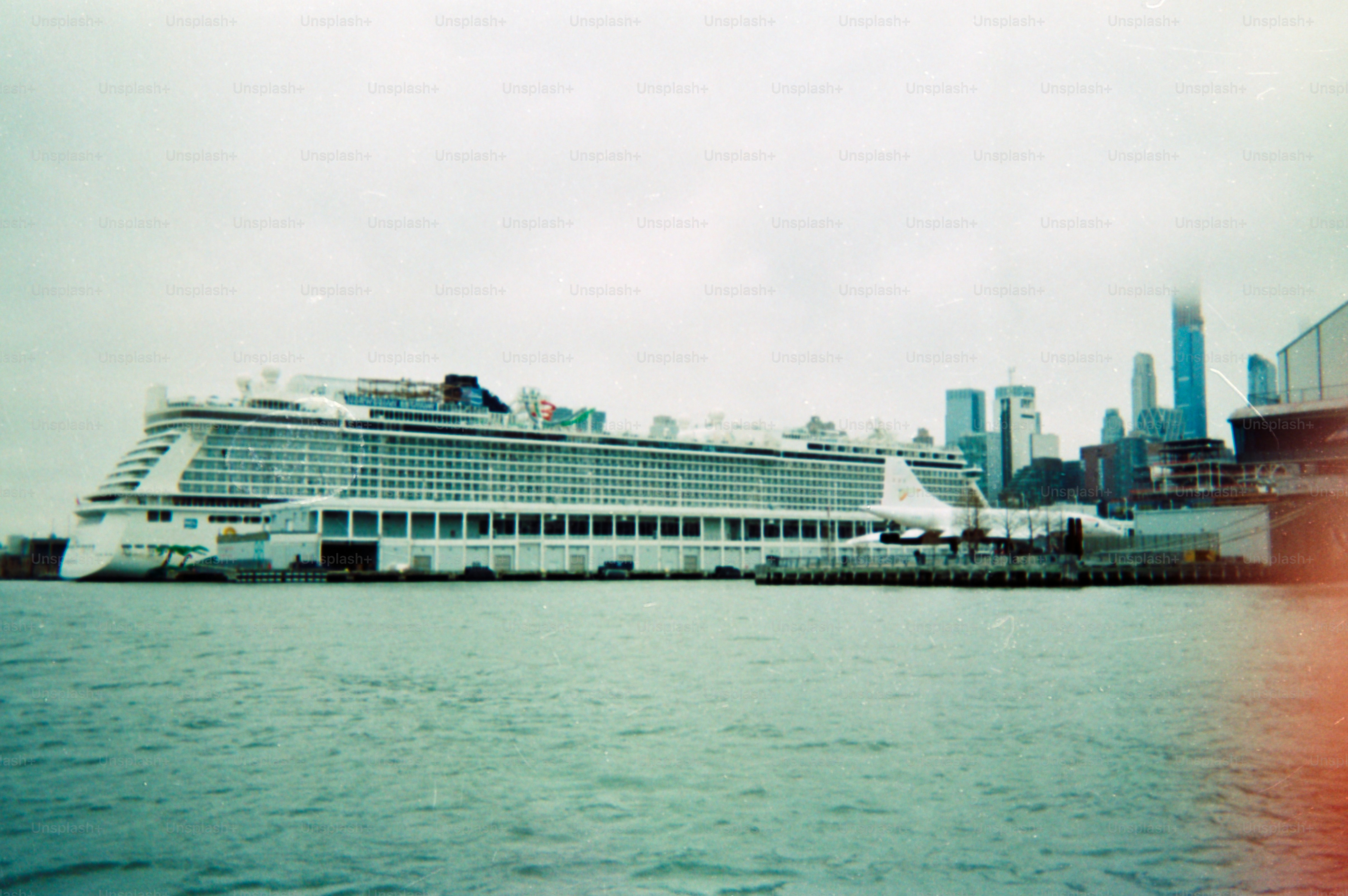 A cruise ship is docked near a city skyline.