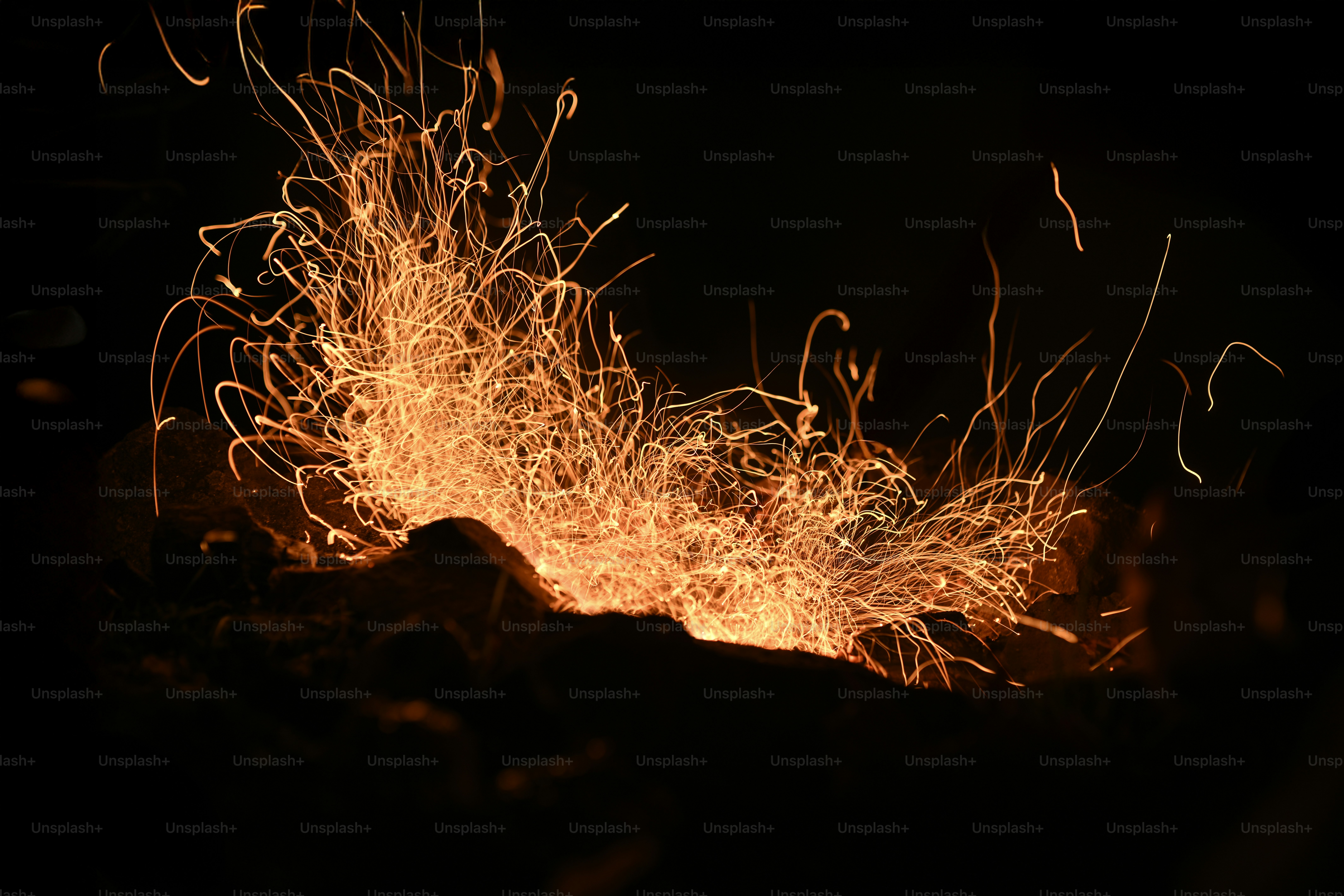 Sparks erupt from a glowing fire.