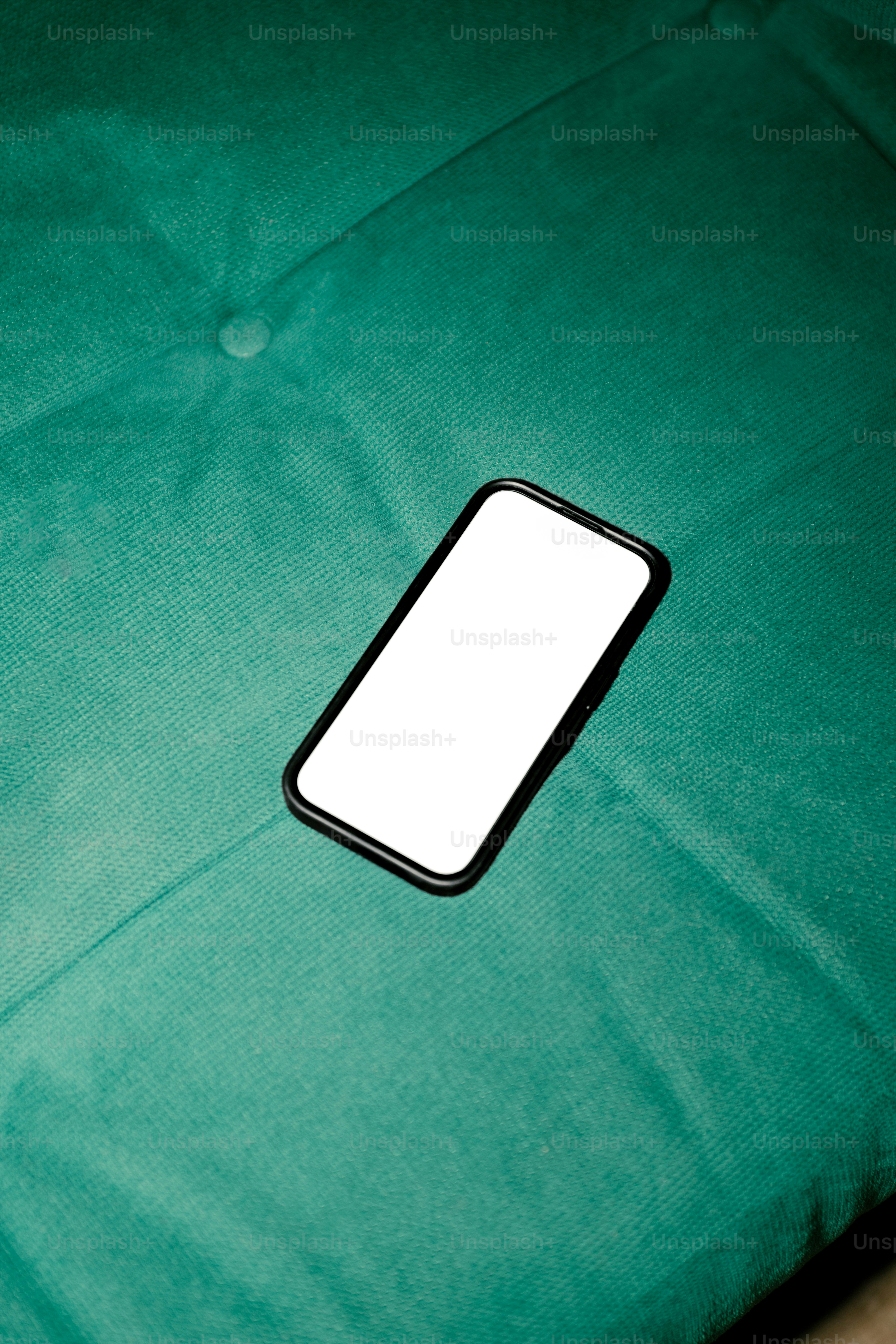 A smartphone with a blank screen is on green fabric.