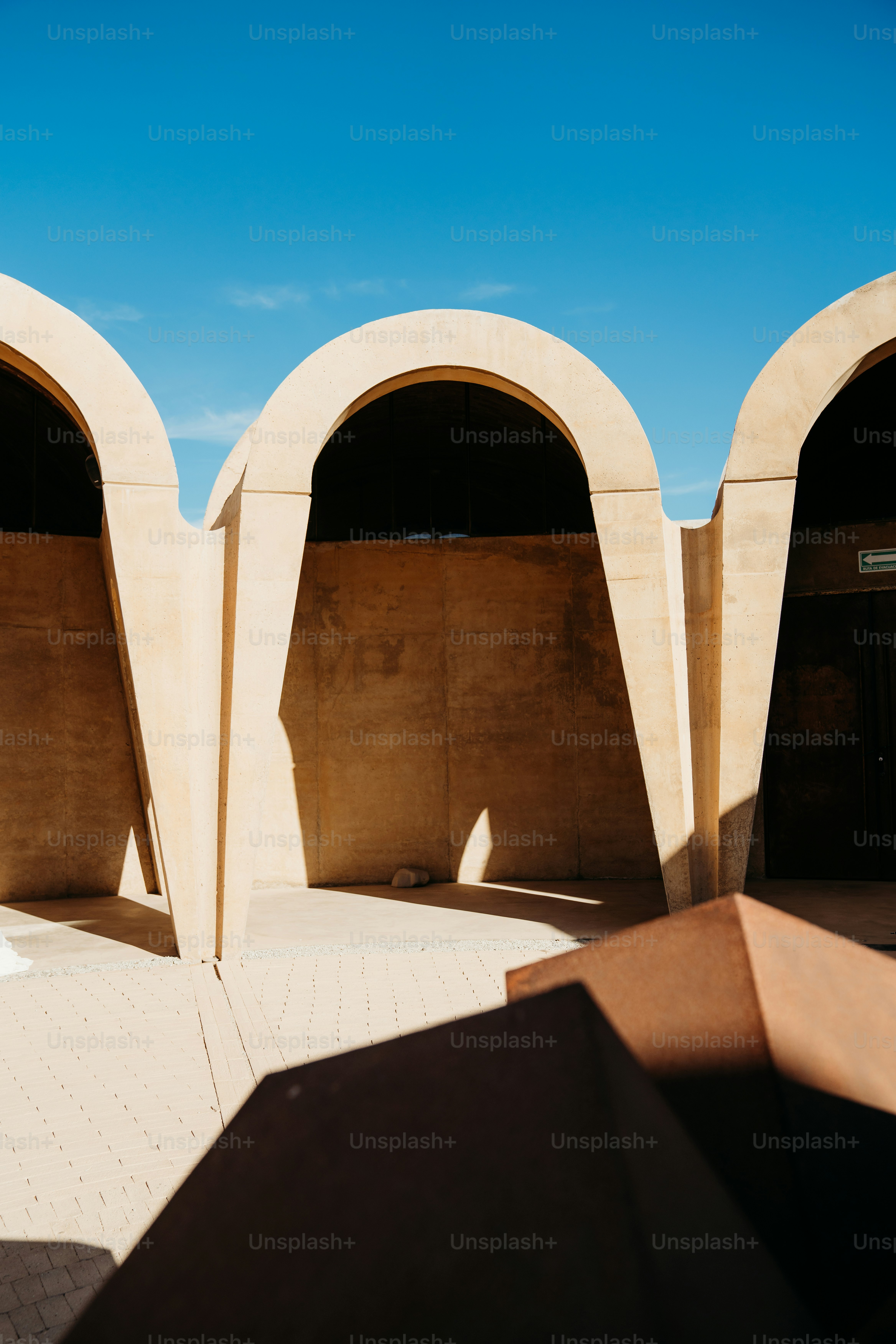 Arched concrete building elements against blue sky.