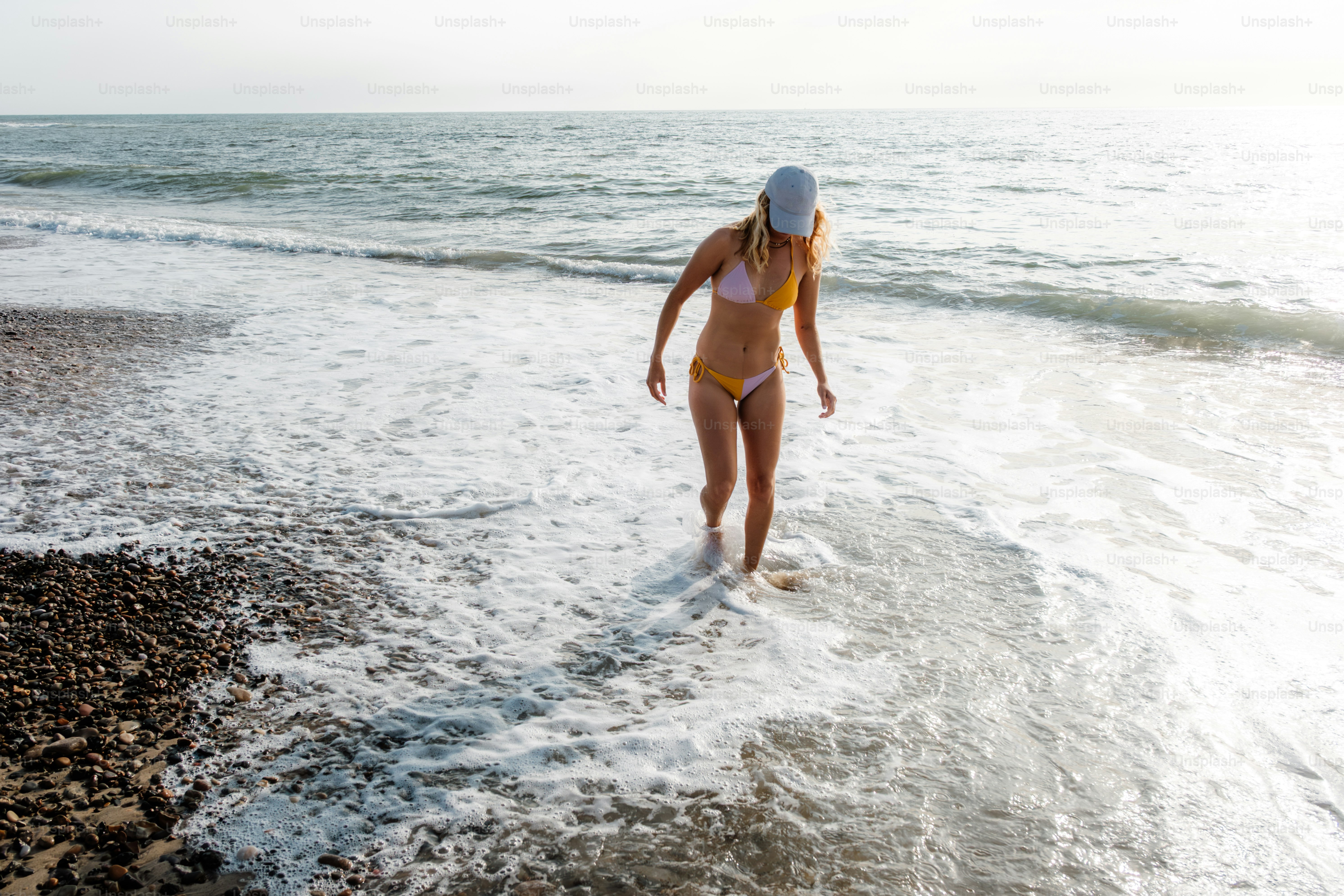 A woman walks into the ocean in a bikini. photo – Beach Image on Unsplash