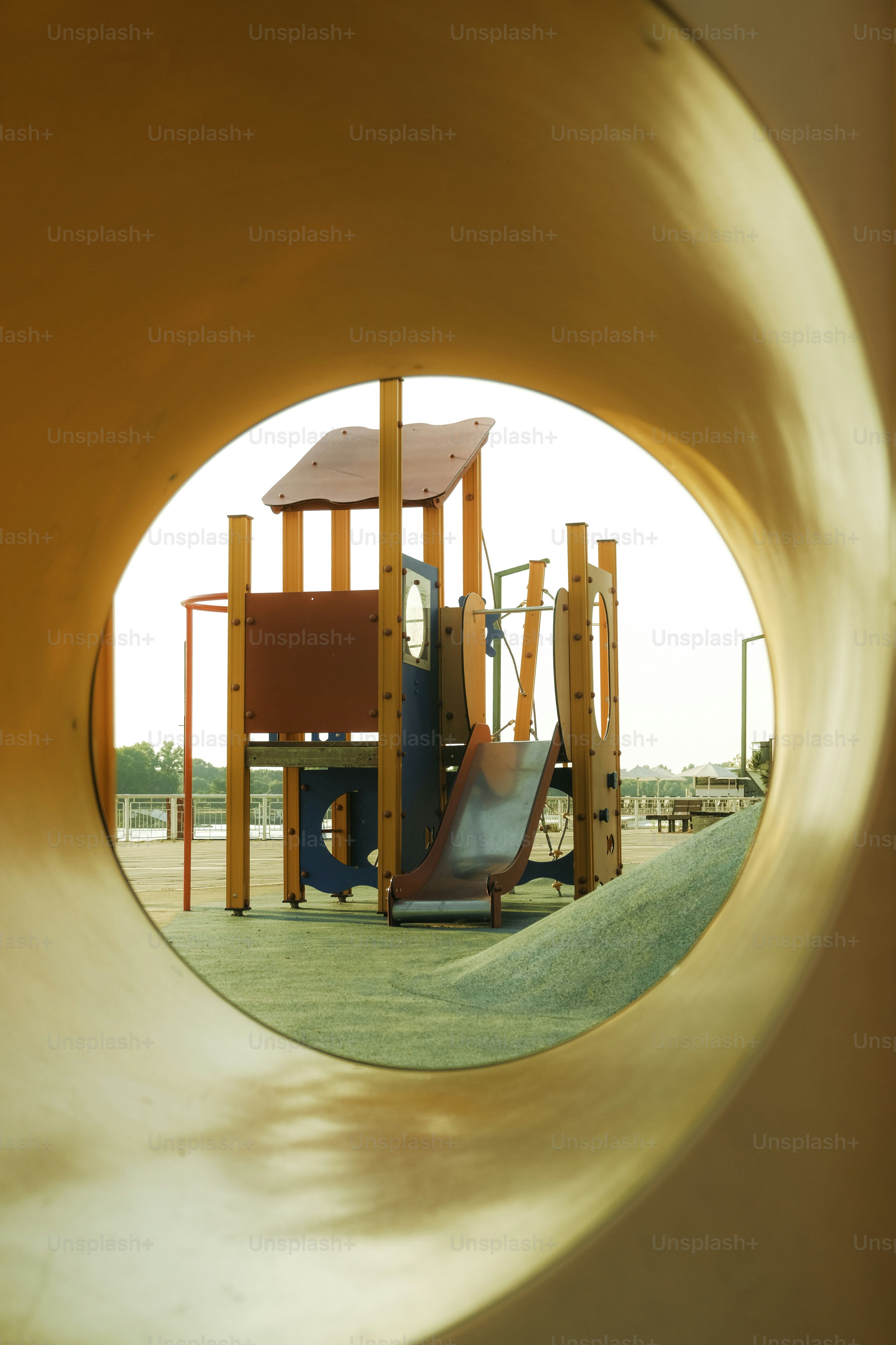 Une aire de jeux vue à travers un tunnel jaune.