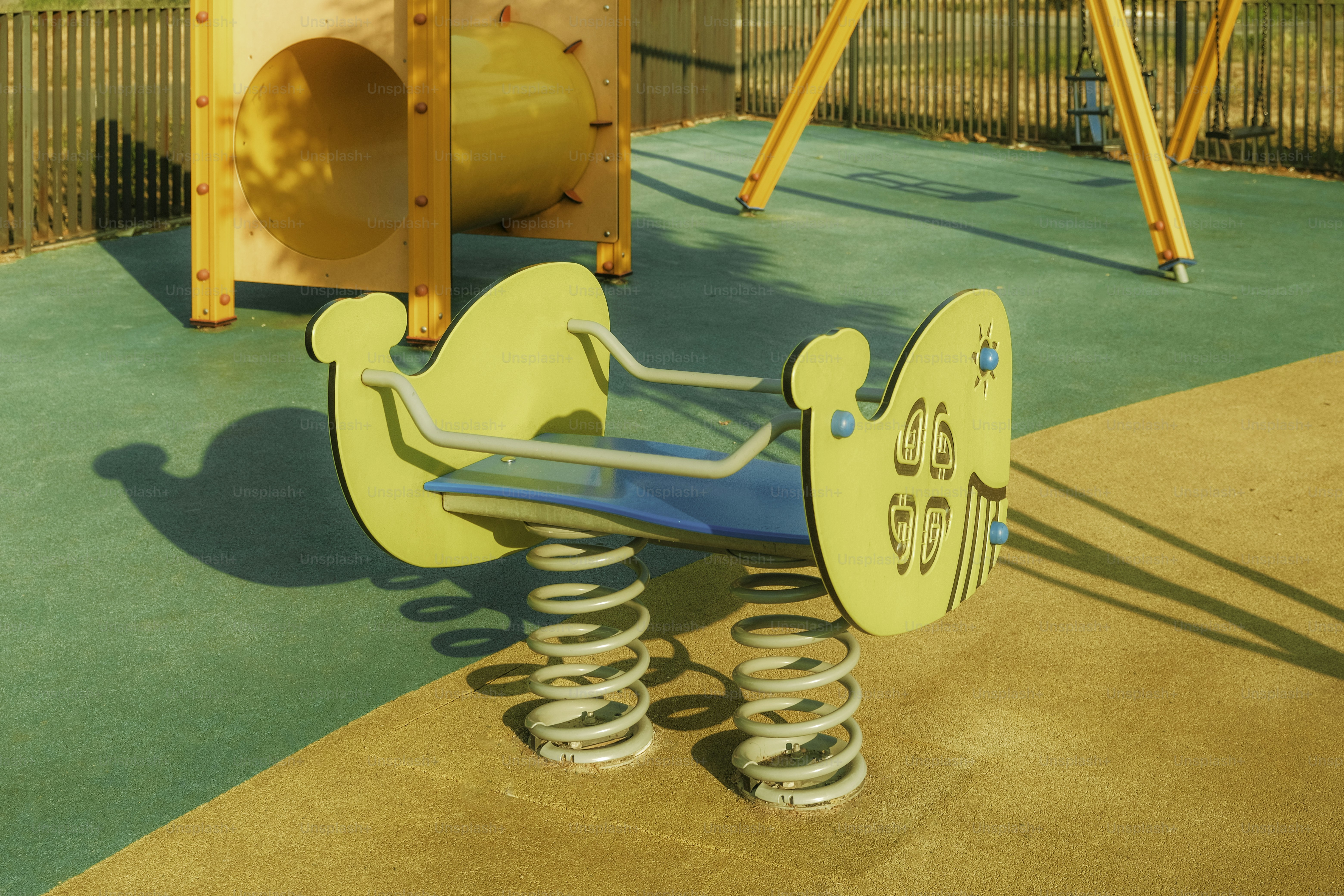 Un cavalier à ressort est sur une aire de jeux ensoleillée pour enfants.
