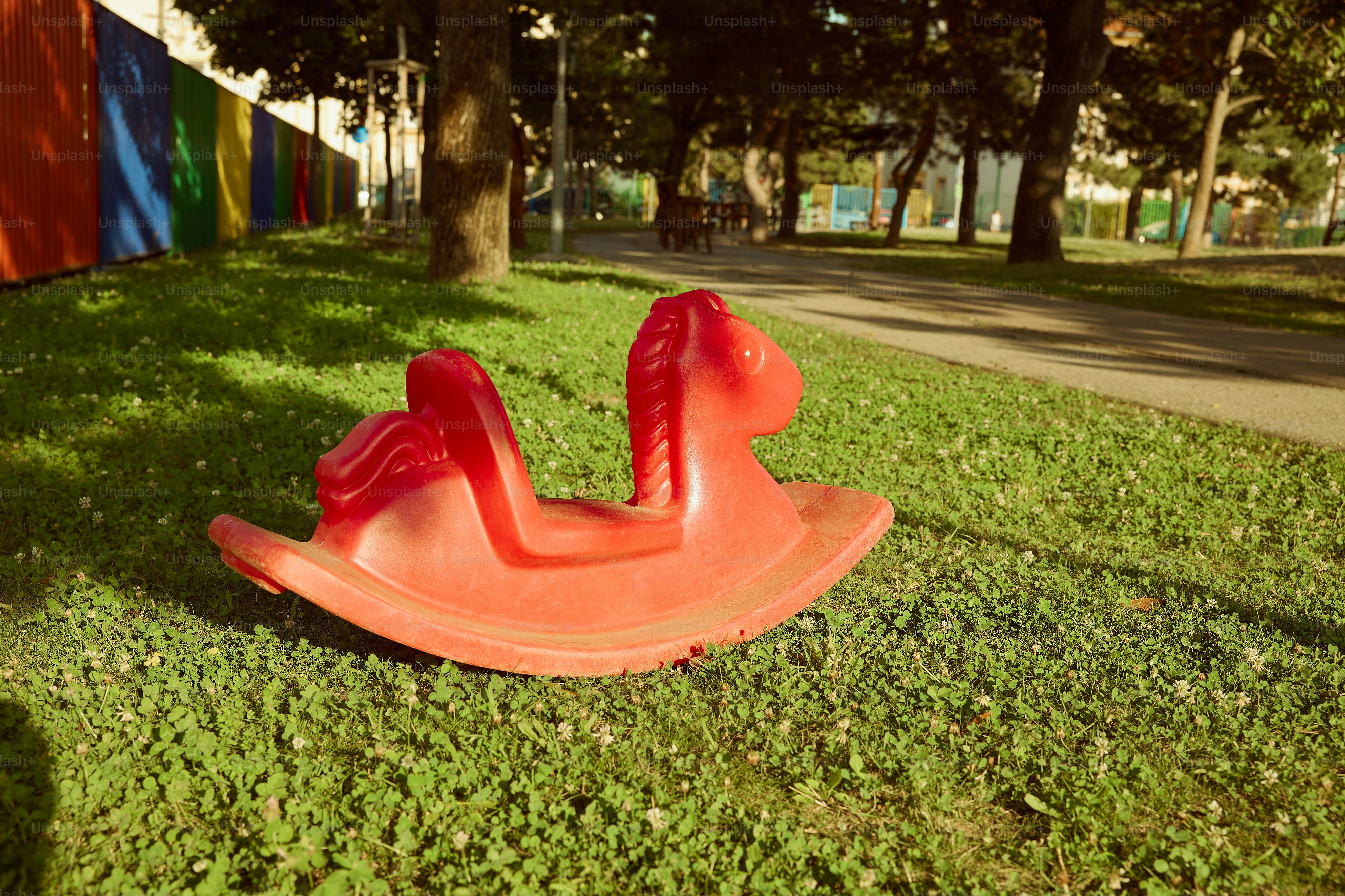 A red rocking horse rests in the park.