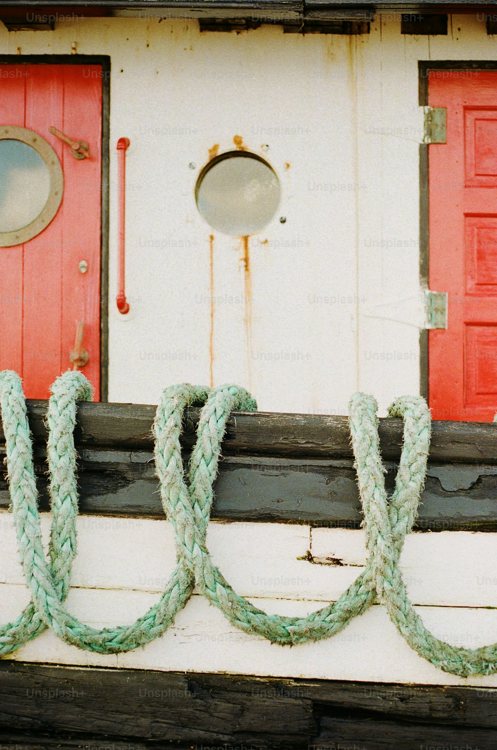 A boat features red doors, porthole, and rope