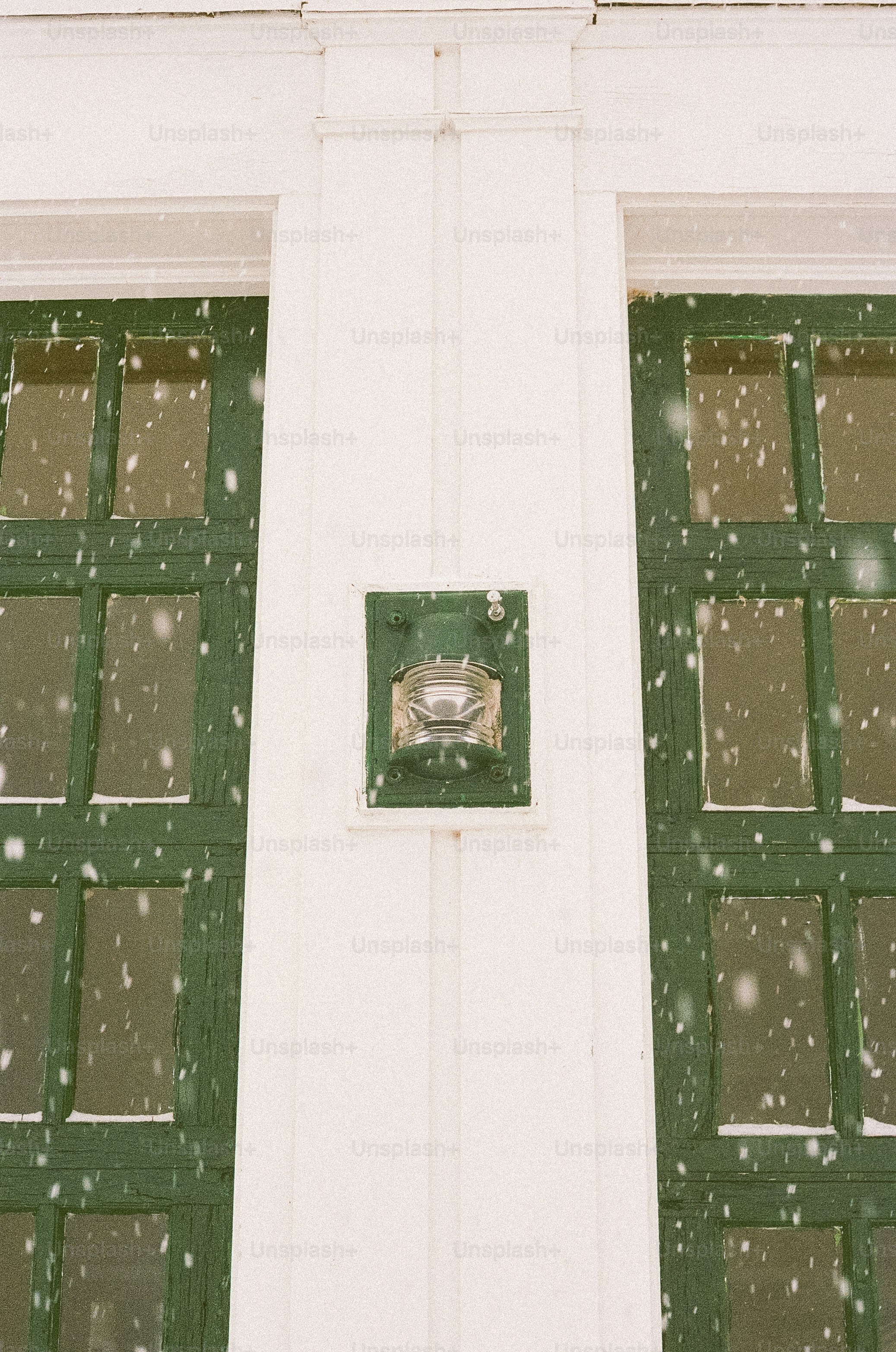 Grüne Fenster sind mit fallendem Schnee bedeckt.