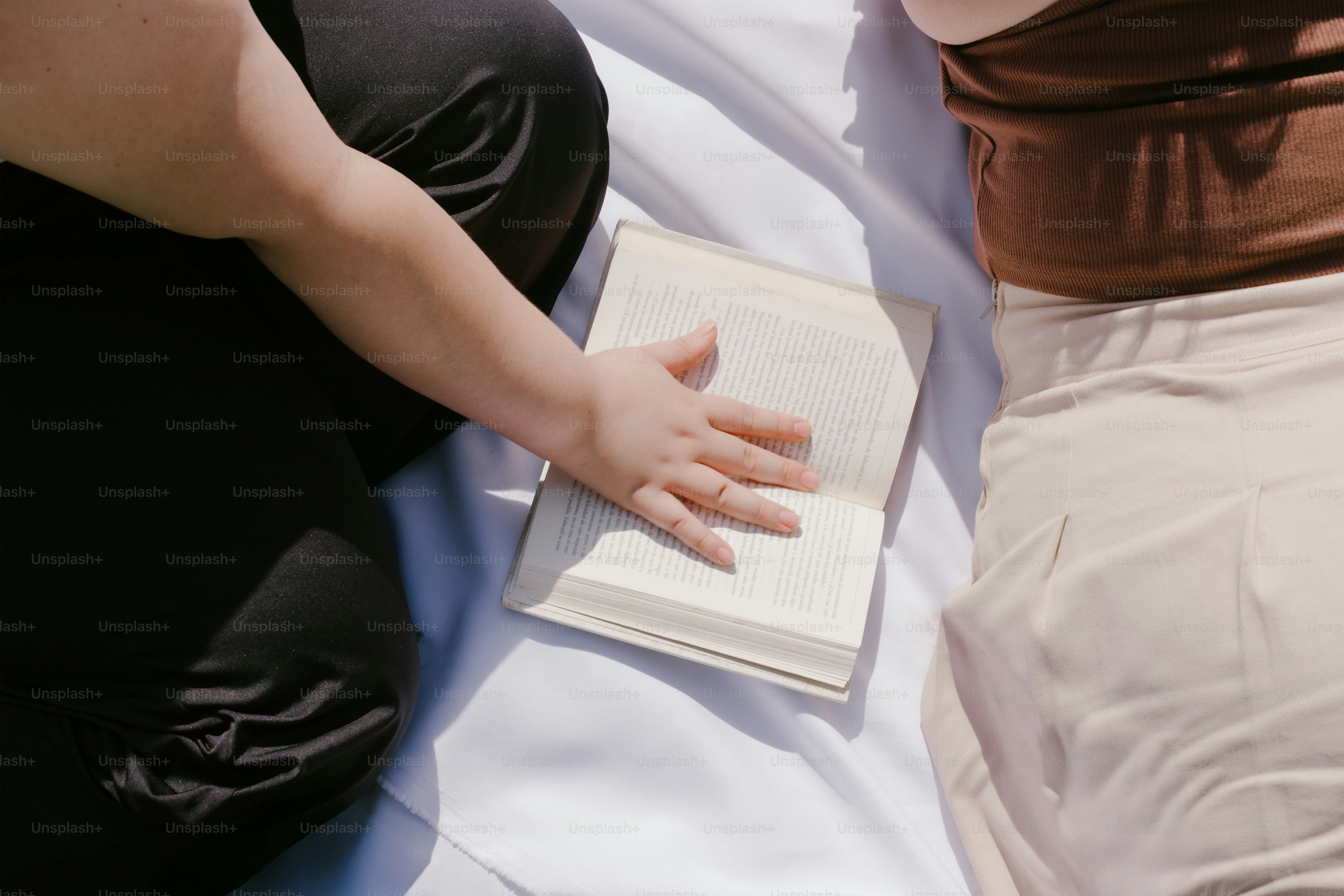 A hand rests on the open pages of a book.