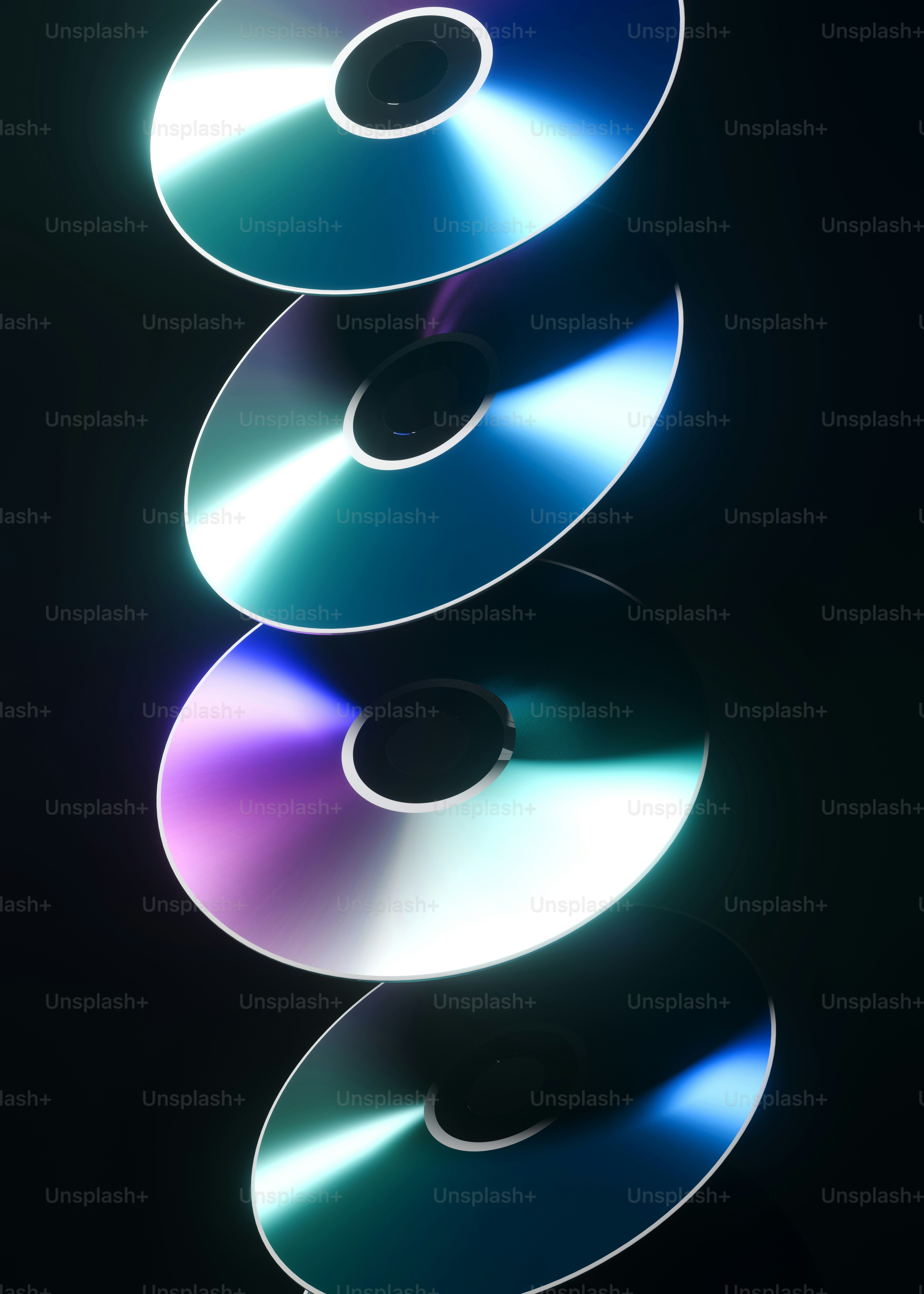 Shiny cds are stacked against a black background.