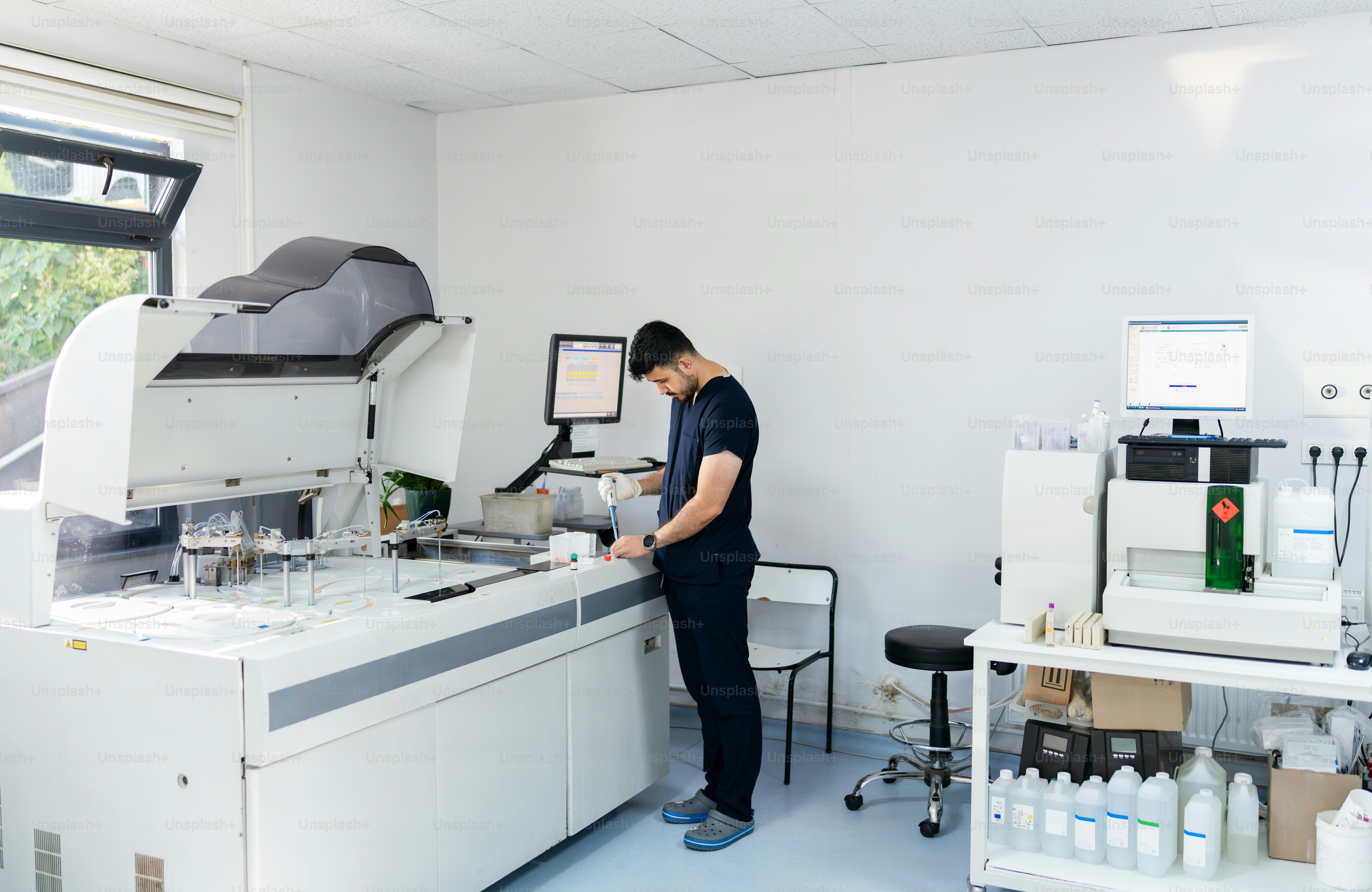 A lab worker operates complex medical equipment. photo – Hospital Image ...