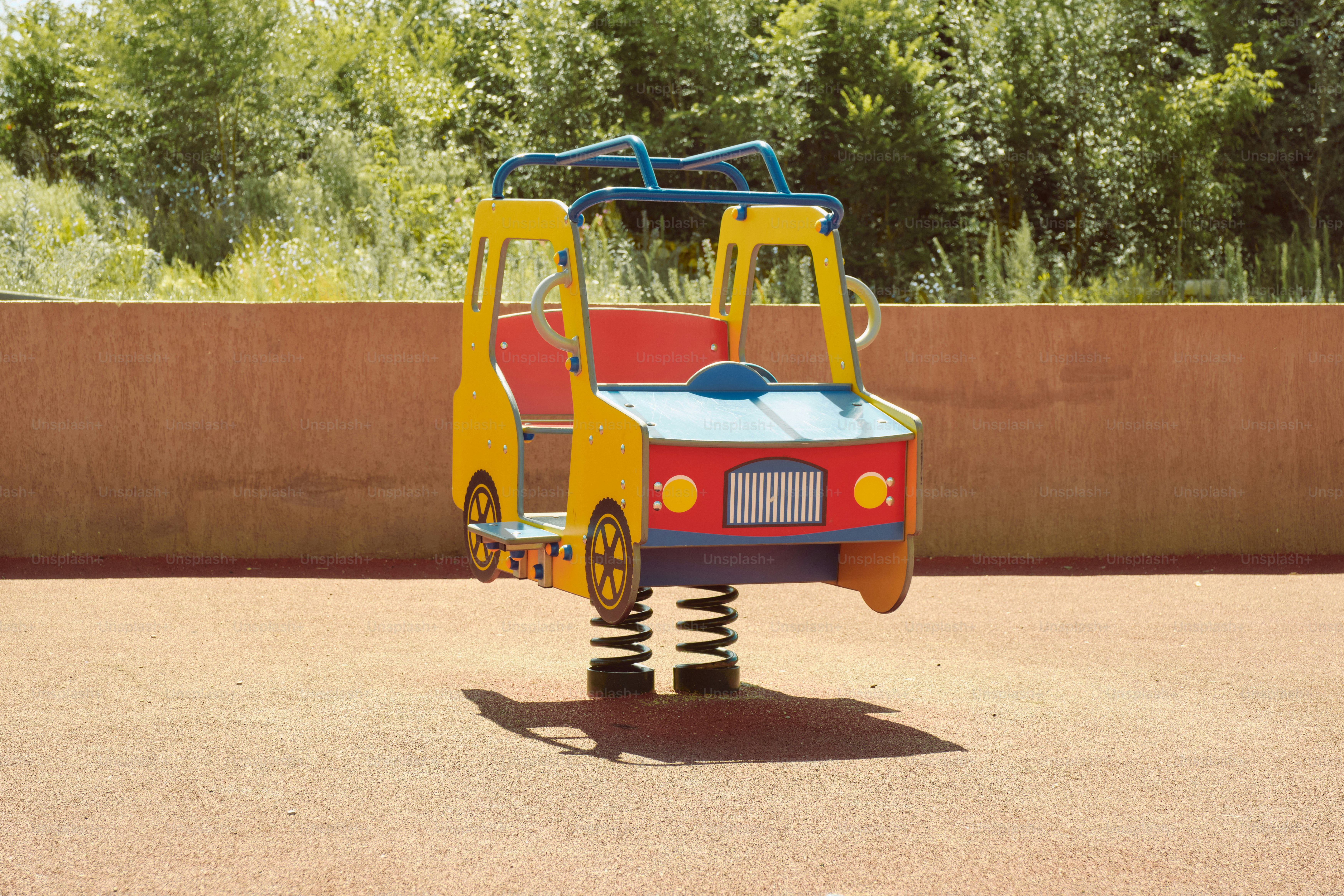 Une voiture colorée montée sur ressorts sur une aire de jeux.