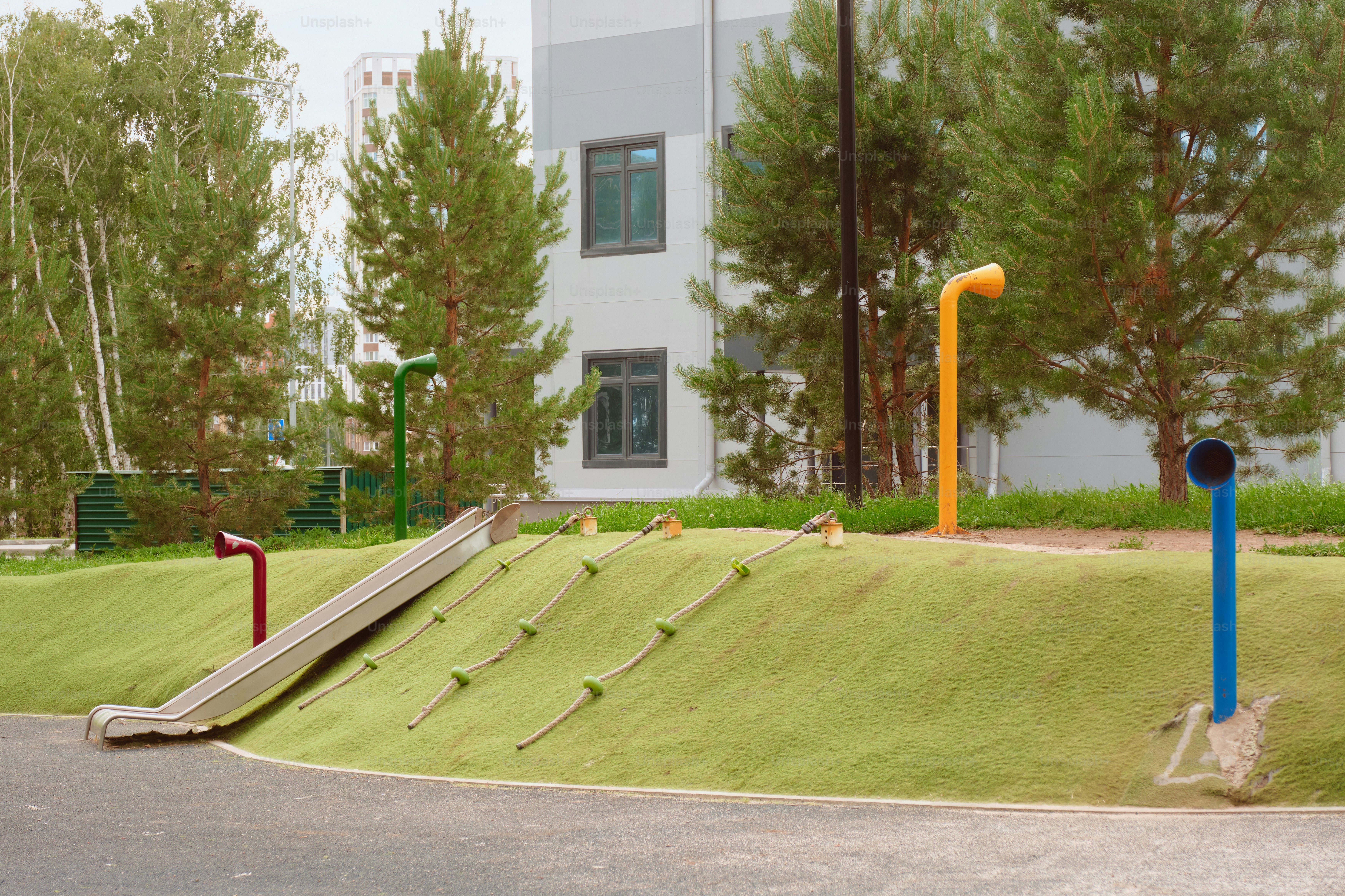 A playground with a slide and colorful poles.